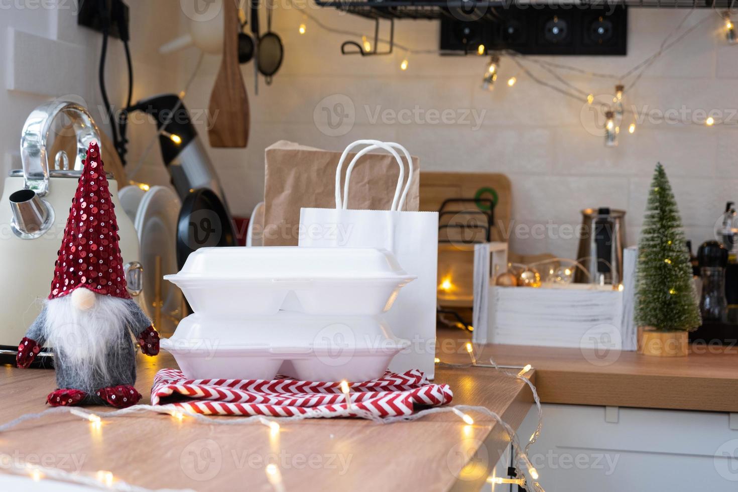 Food delivery service containers on table white scandi festive kitchen in christmas decor. Eve New year, saving time, too lazy to cook, hot order, disposable plastic box in fairy light. mock up photo