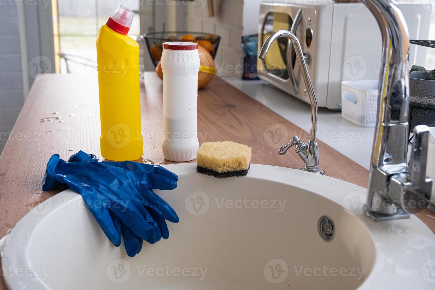 limpieza de la cocina, detergente, polvo seco, esponja, guantes en el fregadero. decoración festiva en la cocina blanca, acogedor interior de la casa foto
