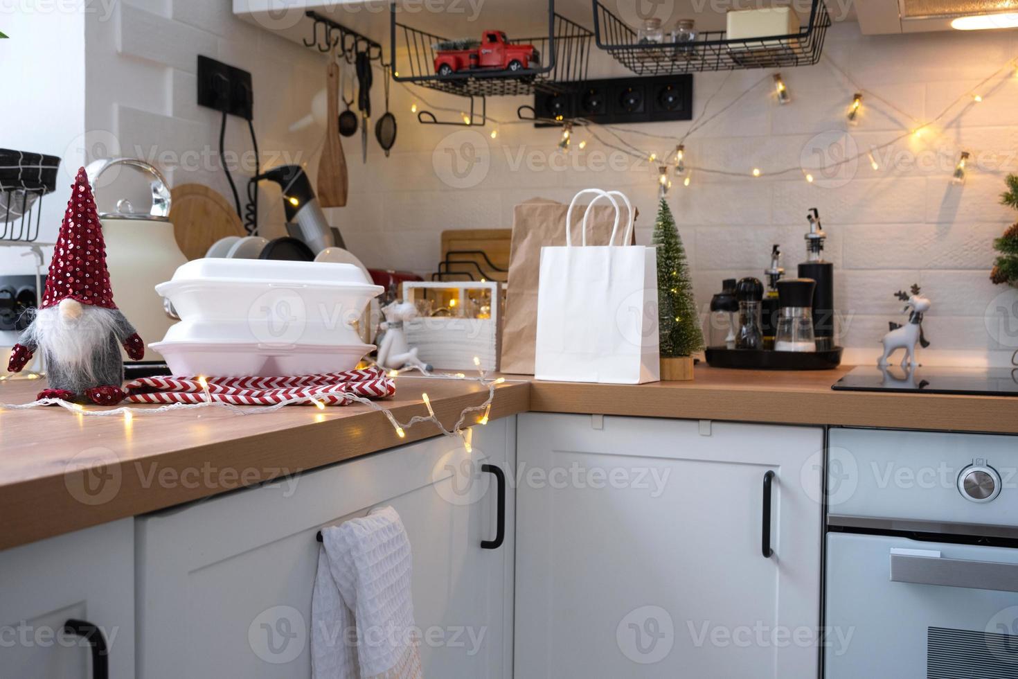 Food delivery service containers on table white scandi festive kitchen in christmas decor. Eve New year, saving time, too lazy to cook, hot order, disposable plastic box in fairy light. mock up photo