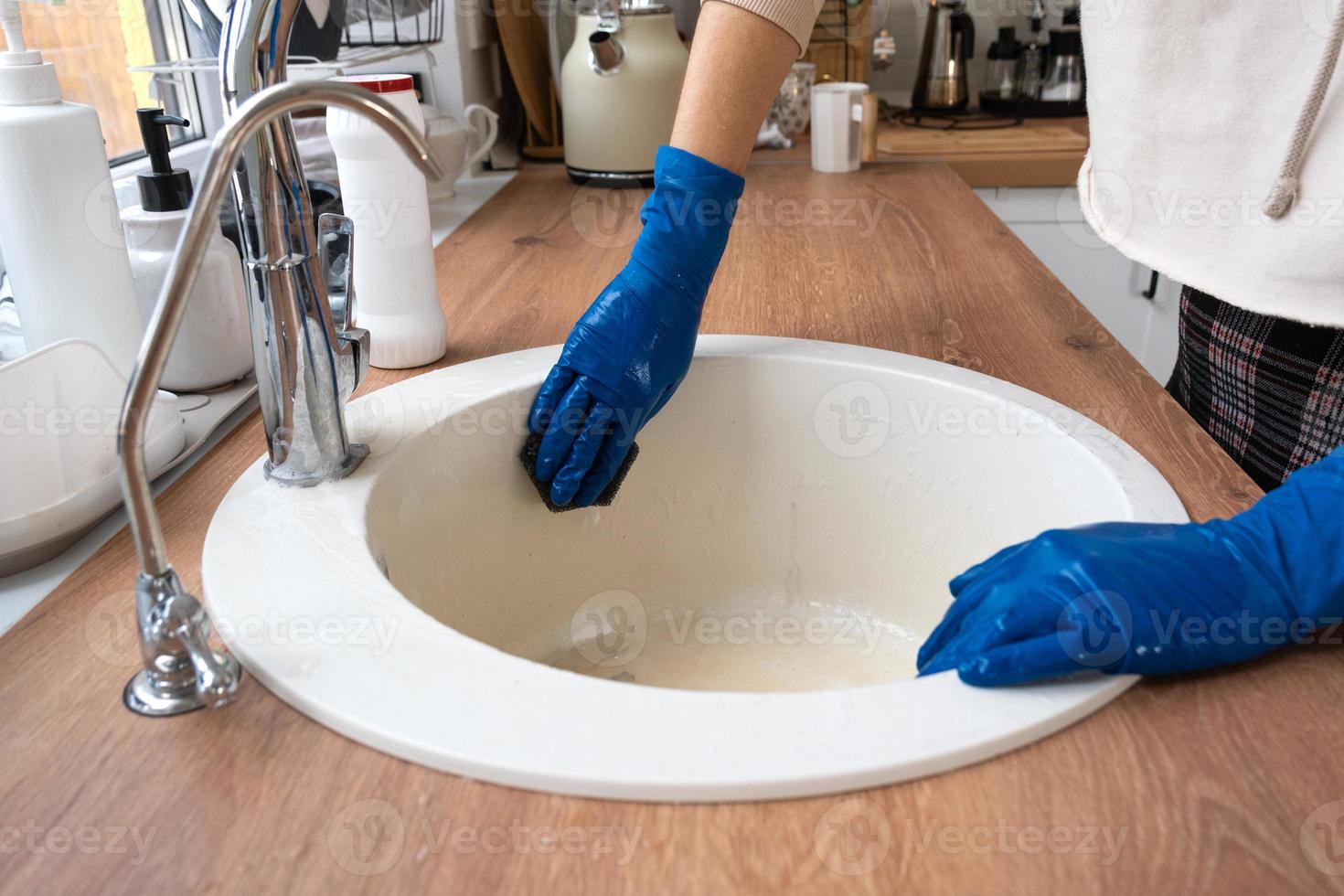 Cleaning sink in kitchen, Hand in gloves and sponge, detergent, dry powder. cozy interior of the home, restoring order, cleanliness, disinfection photo