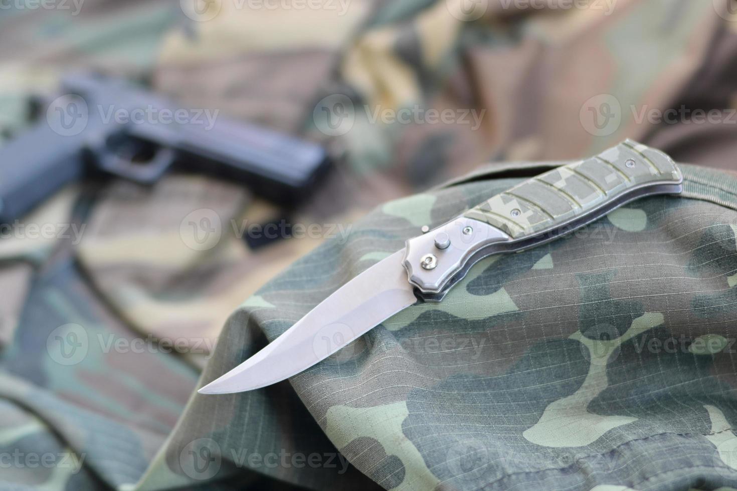 Tactical knife and pistol lie on camouflage green fabric photo