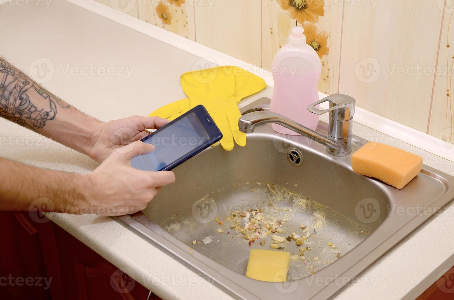 The landlord uses the tablet to call a cleaner in order to clean the clogged kitchen sink photo