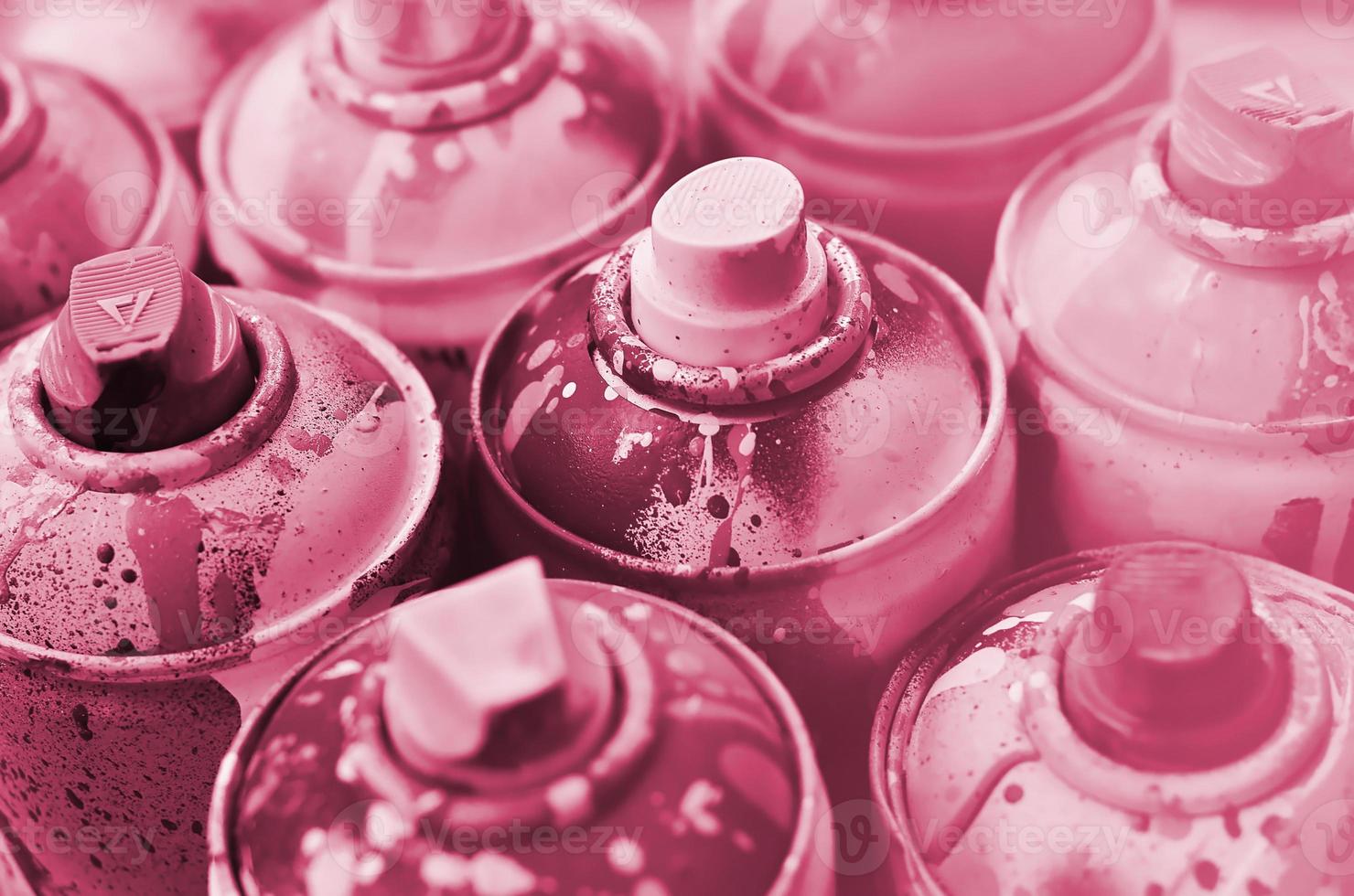 A lot of used spray cans of paint close-up. Dirty and smeared cans for drawing graffiti. The concept of a sweeping and careless drawing of paint. Image toned in Viva Magenta, color of the year photo