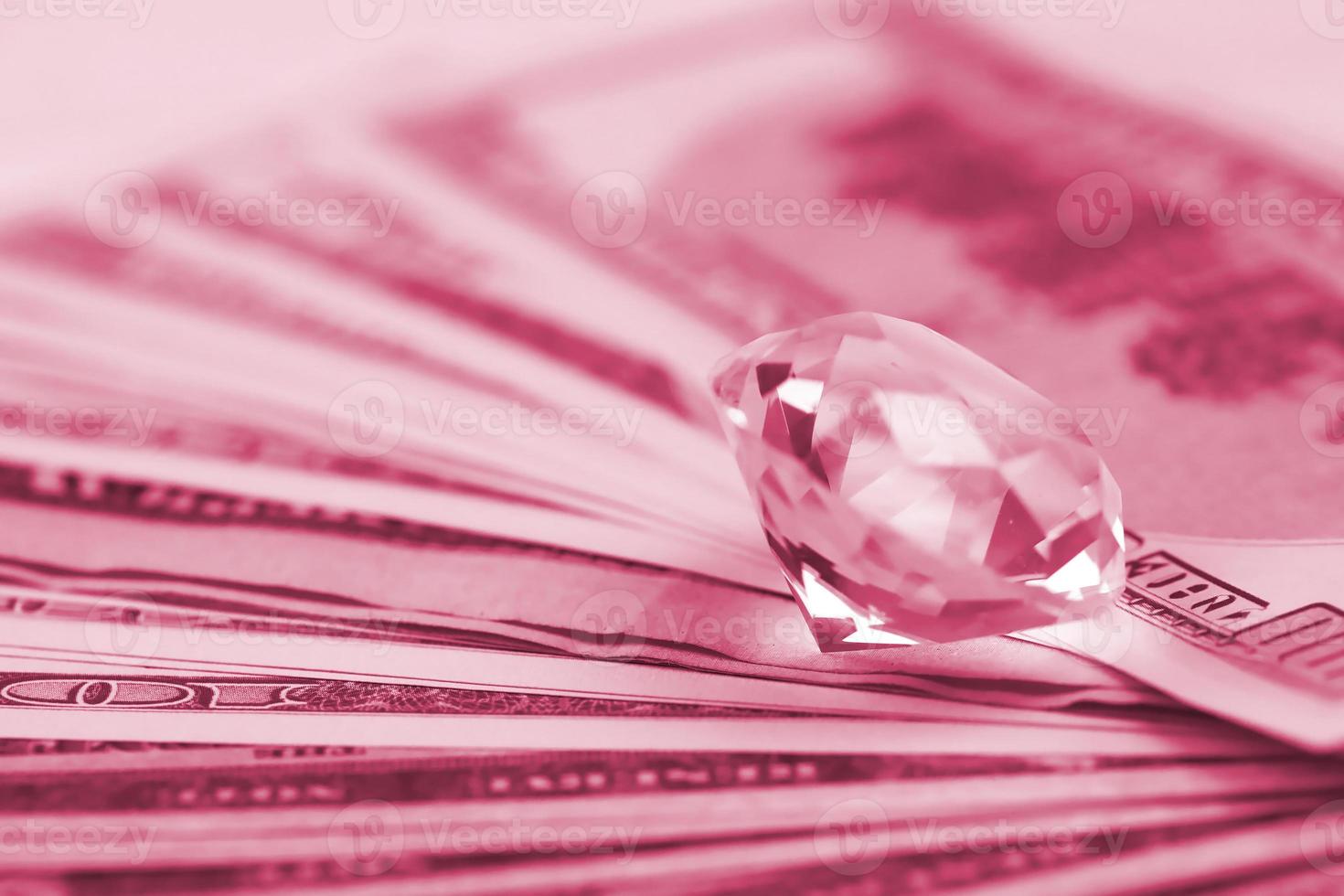 nosotros billetes de dinero con un gran diamante de cerca. gran cantidad de dólares y una enorme gema transparente sobre la mesa. imagen de negocios y joyería tonificada en viva magenta, color del año 2023 foto