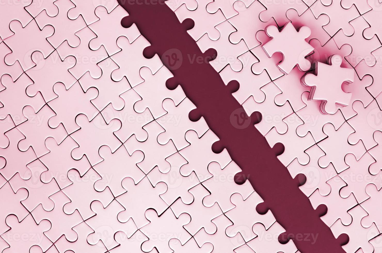 Path is laid on the platform of a white folded jigsaw puzzle. The missing elements of the puzzle are stacked nearby. tone Image toned in Viva Magenta, color of the 2023 year photo