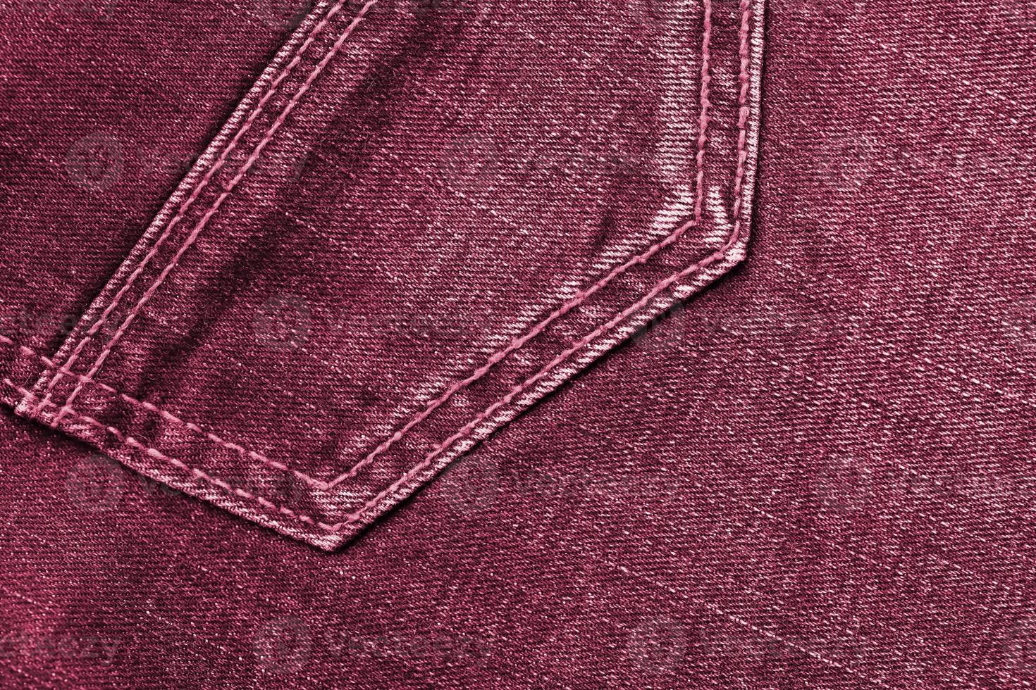 Detailed abstract texture of dark blue denim cloth. Background image of old used denim trousers fabric Image toned in Viva Magenta, color of the 2023 year photo