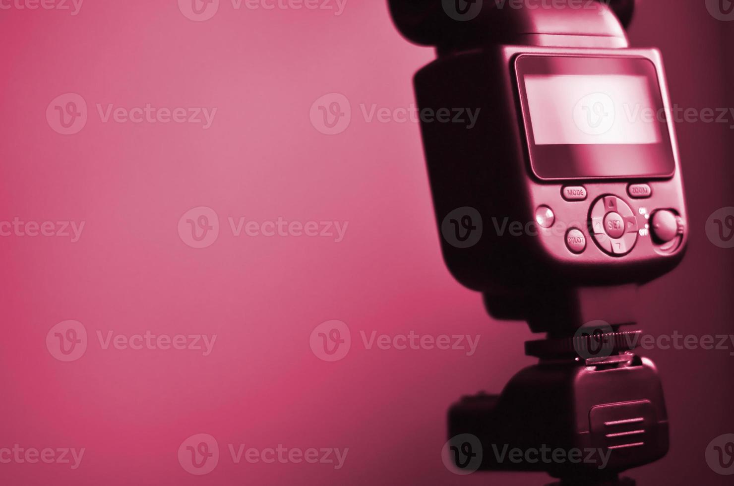 Speedlight gun with trigger set mounted on tripod. tone Image toned in Viva Magenta, color of the 2023 year photo