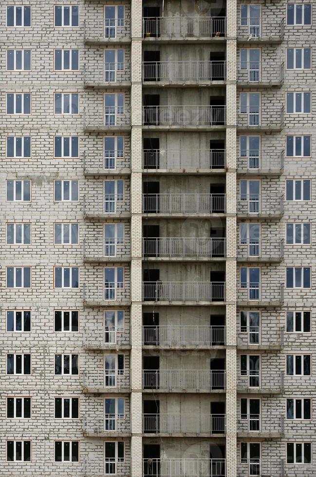 Textured pattern of a russian whitestone residential house building wall with many windows and balcony under construction photo