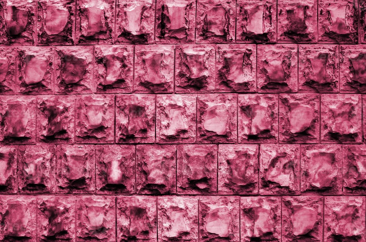 Texture design of the foundation or walls of buildings in the form of rectangular tiles made of solid granite stone with sharp corners Image toned in Viva Magenta, color of the 2023 year photo