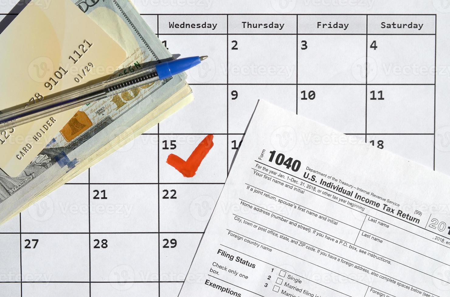 1040 Individual Income Tax Return blank with credit card on dollar bills and pen on calendar page with marked 15th April photo