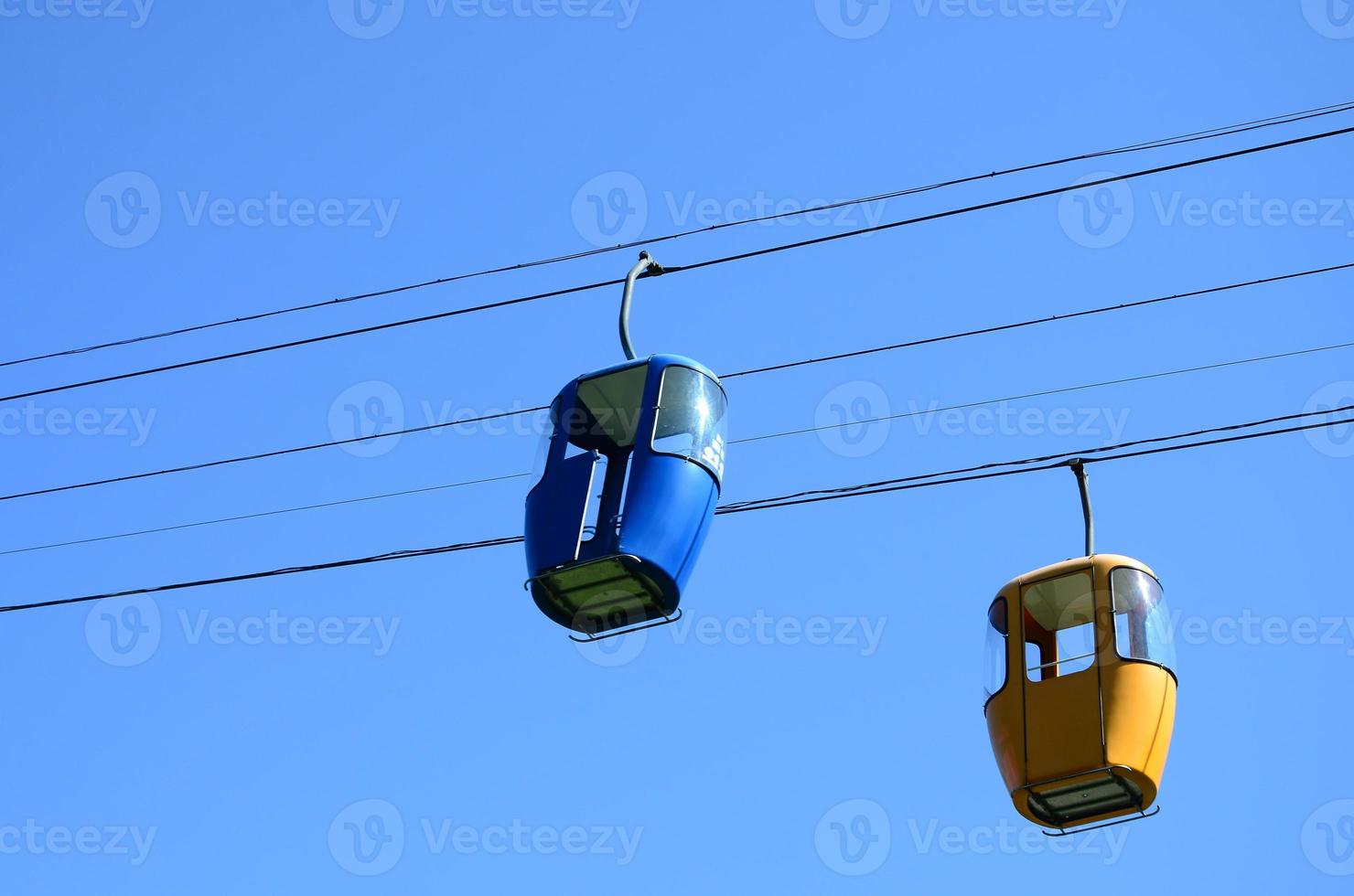 Blue and yellow passenger cable way cabins in the clear sky photo