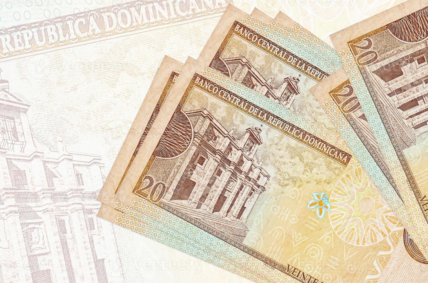 Los billetes de 20 pesos dominicanos se encuentran apilados sobre el fondo de un gran billete semitransparente. presentación abstracta de la moneda nacional foto