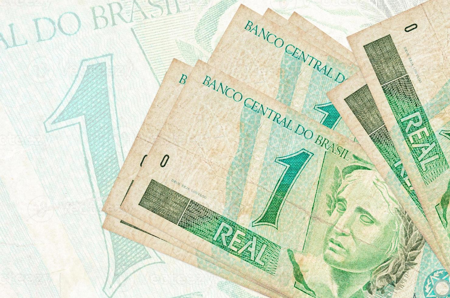 1 billete real brasileño se encuentra apilado en el fondo de un gran billete semitransparente. presentación abstracta de la moneda nacional foto