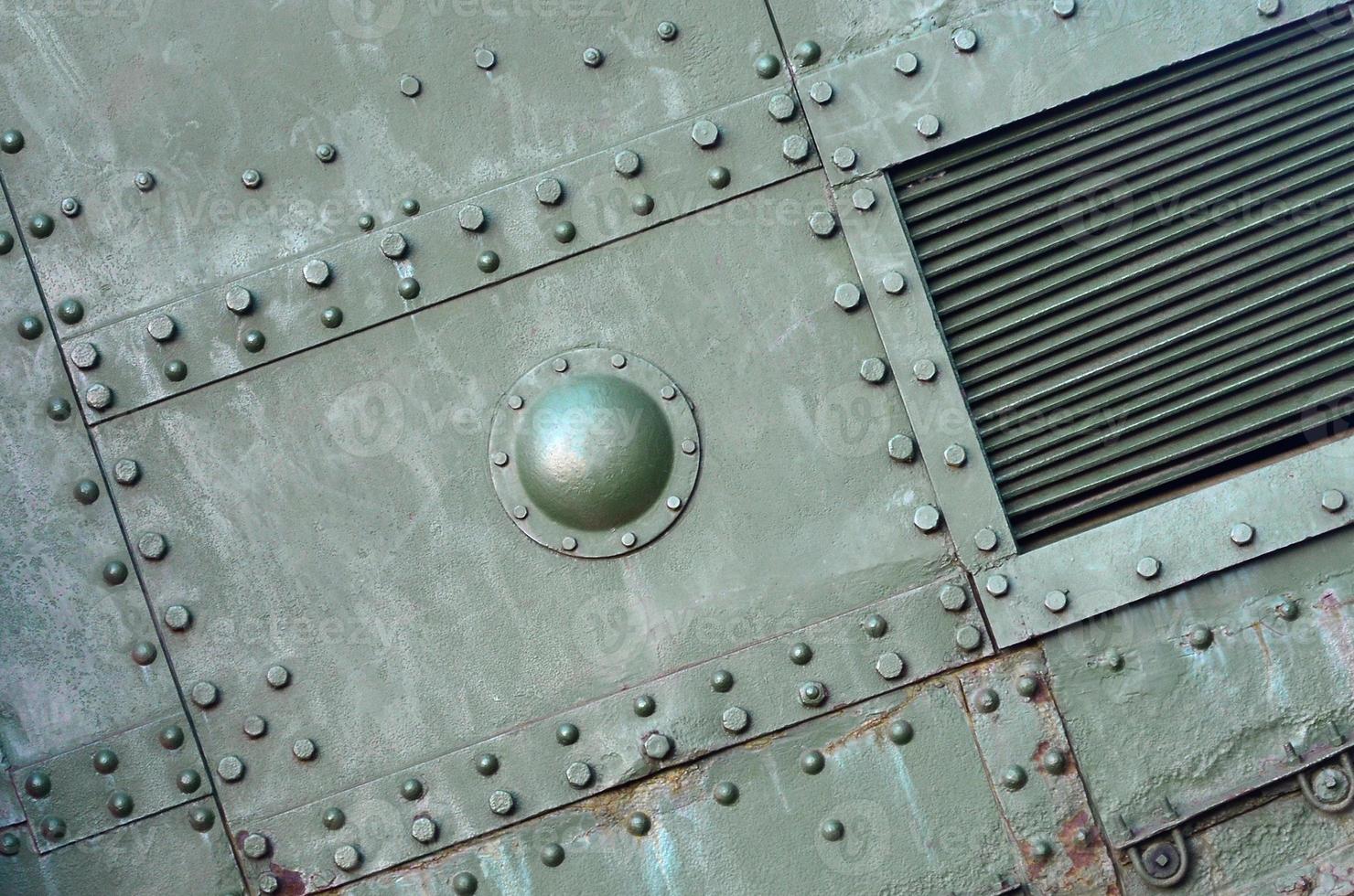 Texture of tank side wall, made of metal and reinforced with a multitude of bolts and rivets photo