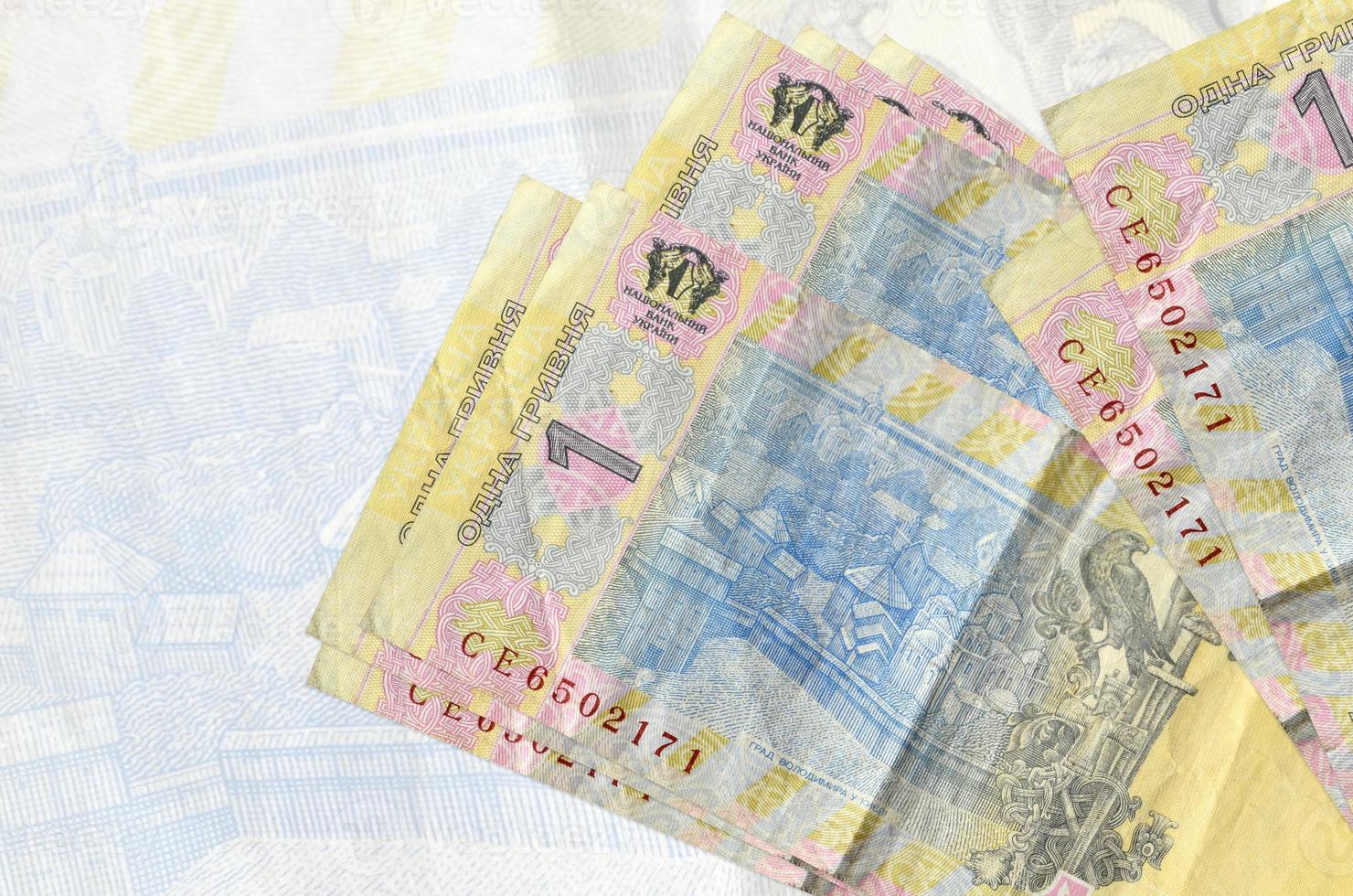 1 Ukrainian hryvnia bills lies in stack on background of big semi-transparent banknote. Abstract presentation of national currency photo
