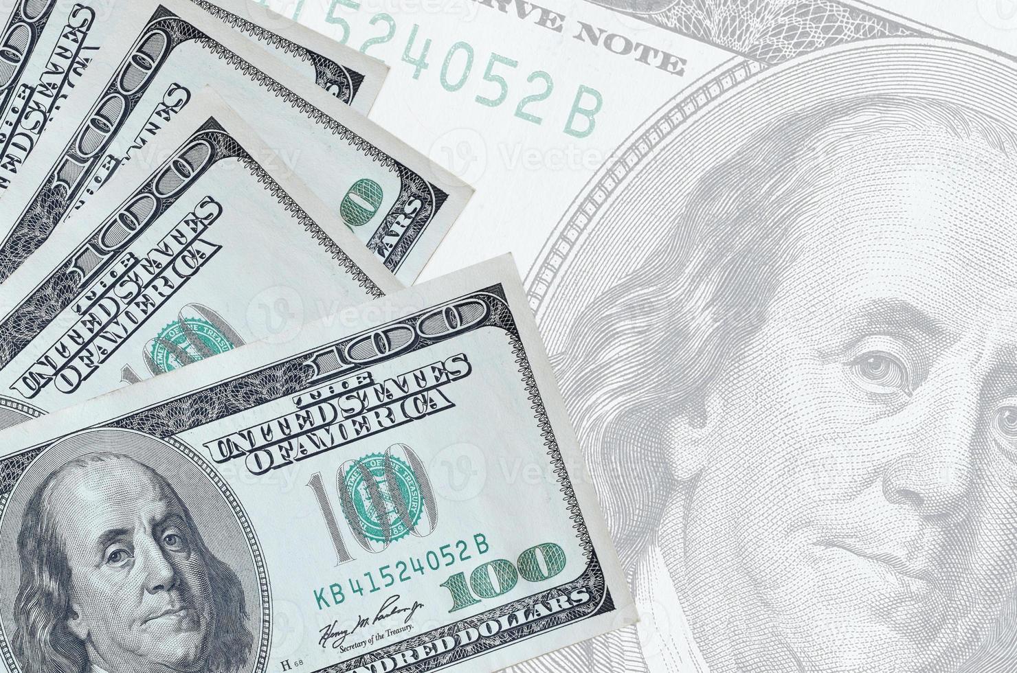 100 US dollars bills lies in stack on background of big semi-transparent banknote. Abstract business background photo