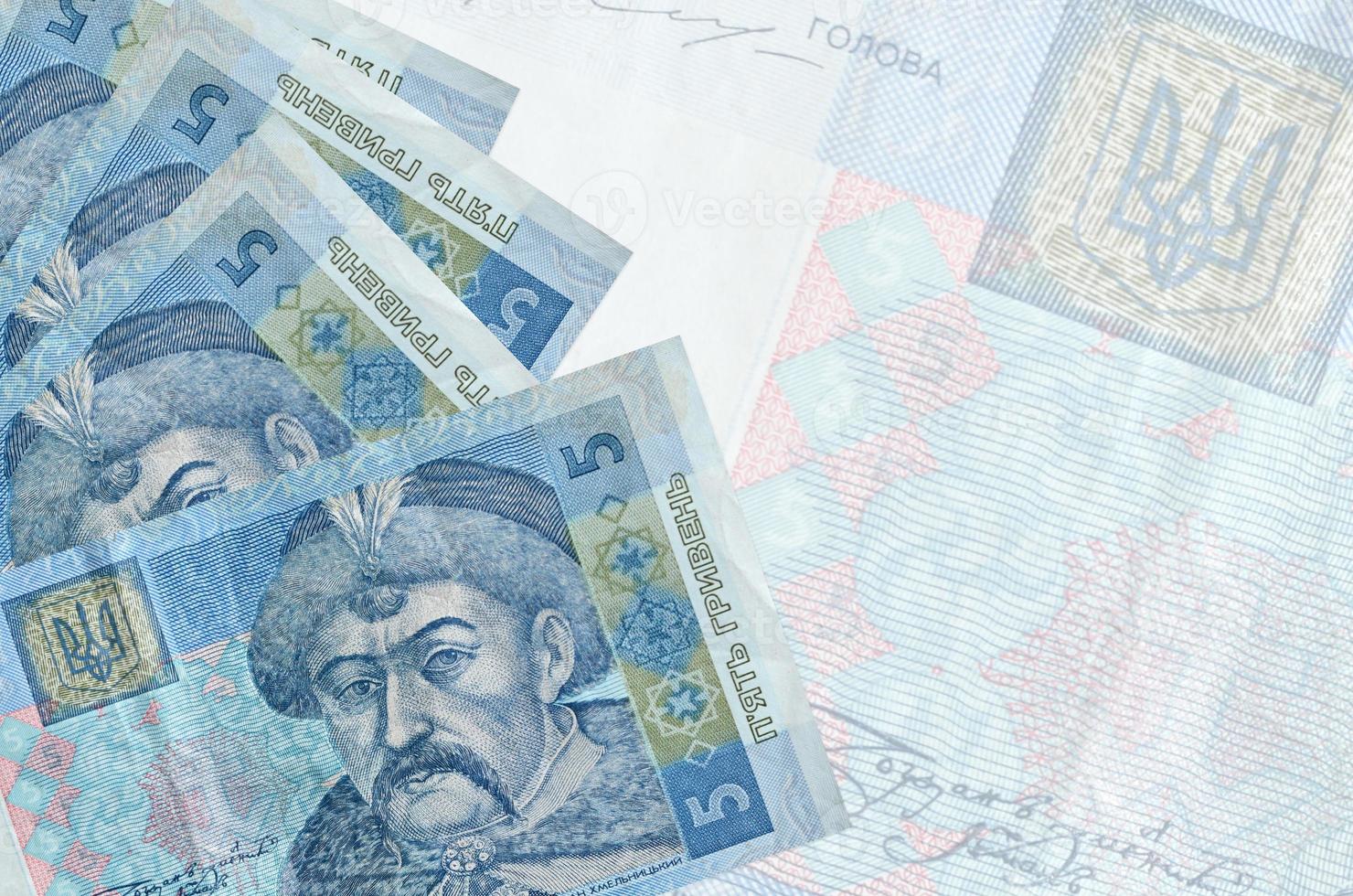 5 Ukrainian hryvnias bills lies in stack on background of big semi-transparent banknote. Abstract business background photo