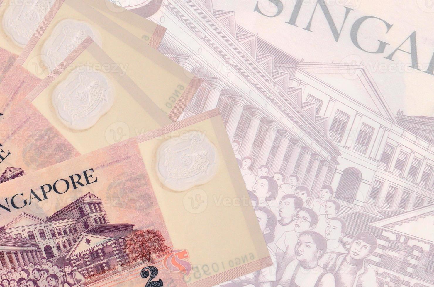 2 Singaporean dollars bills lies in stack on background of big semi-transparent banknote. Abstract business background photo