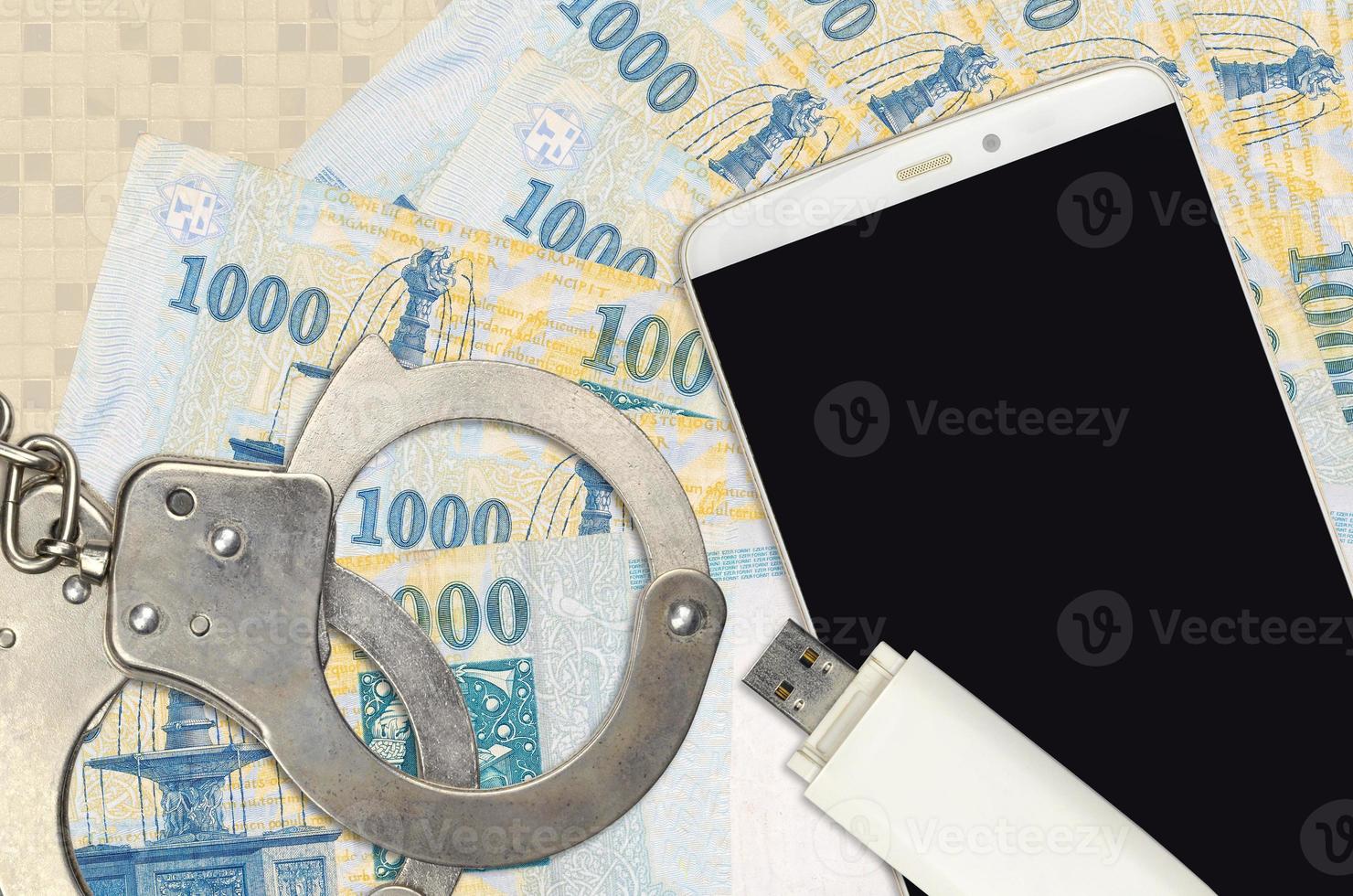 1000 Hungarian forint bills and smartphone with police handcuffs. Concept of hackers phishing attacks, illegal scam or malware soft distribution photo