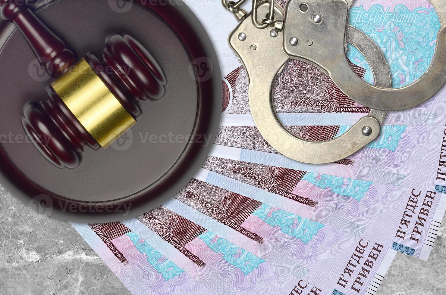 50 Ukrainian hryvnias bills and judge hammer with police handcuffs on court desk. Concept of judicial trial or bribery. Tax avoidance photo