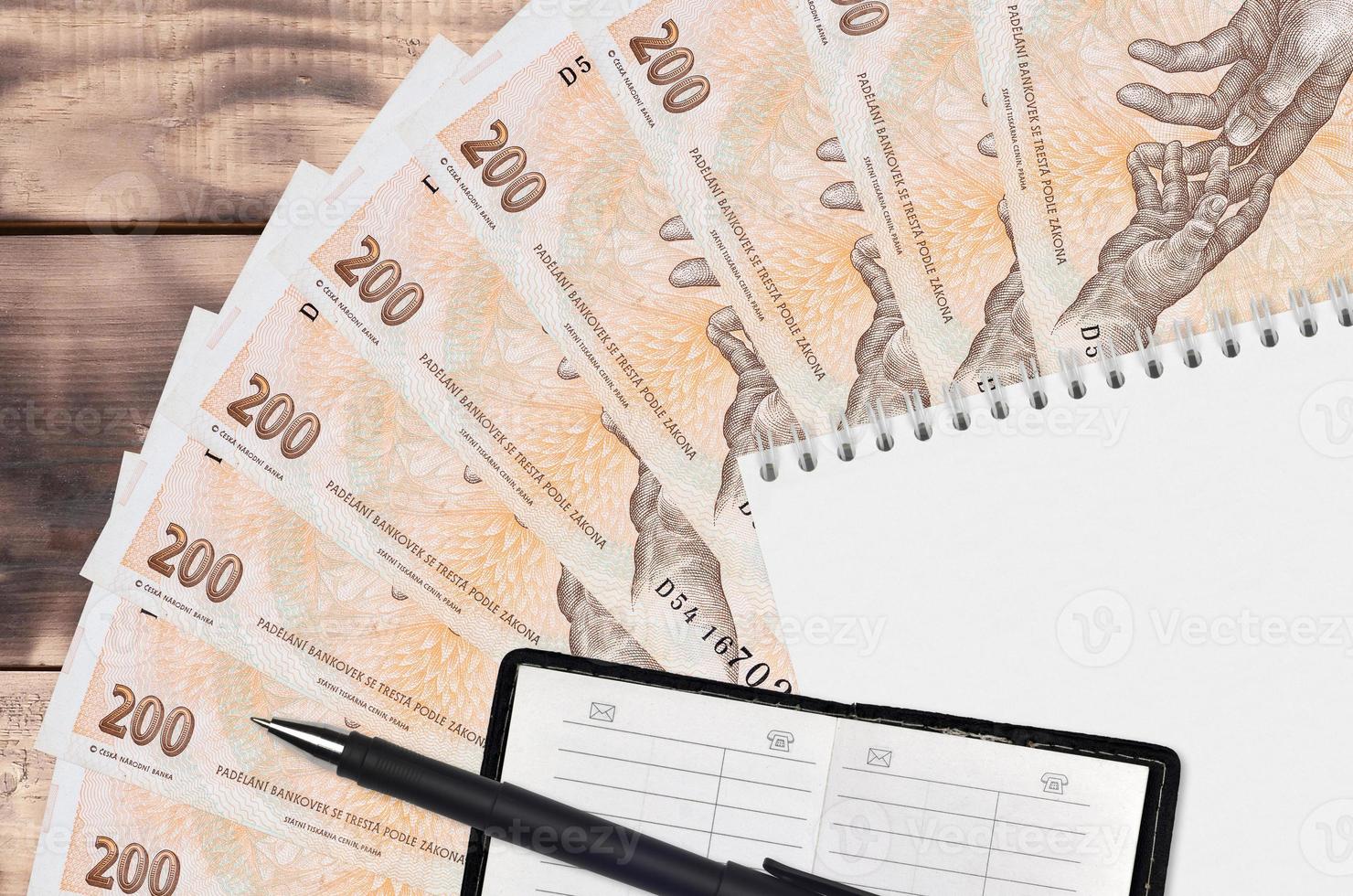 200 Czech korun bills fan and notepad with contact book and black pen. Concept of financial planning and business strategy photo