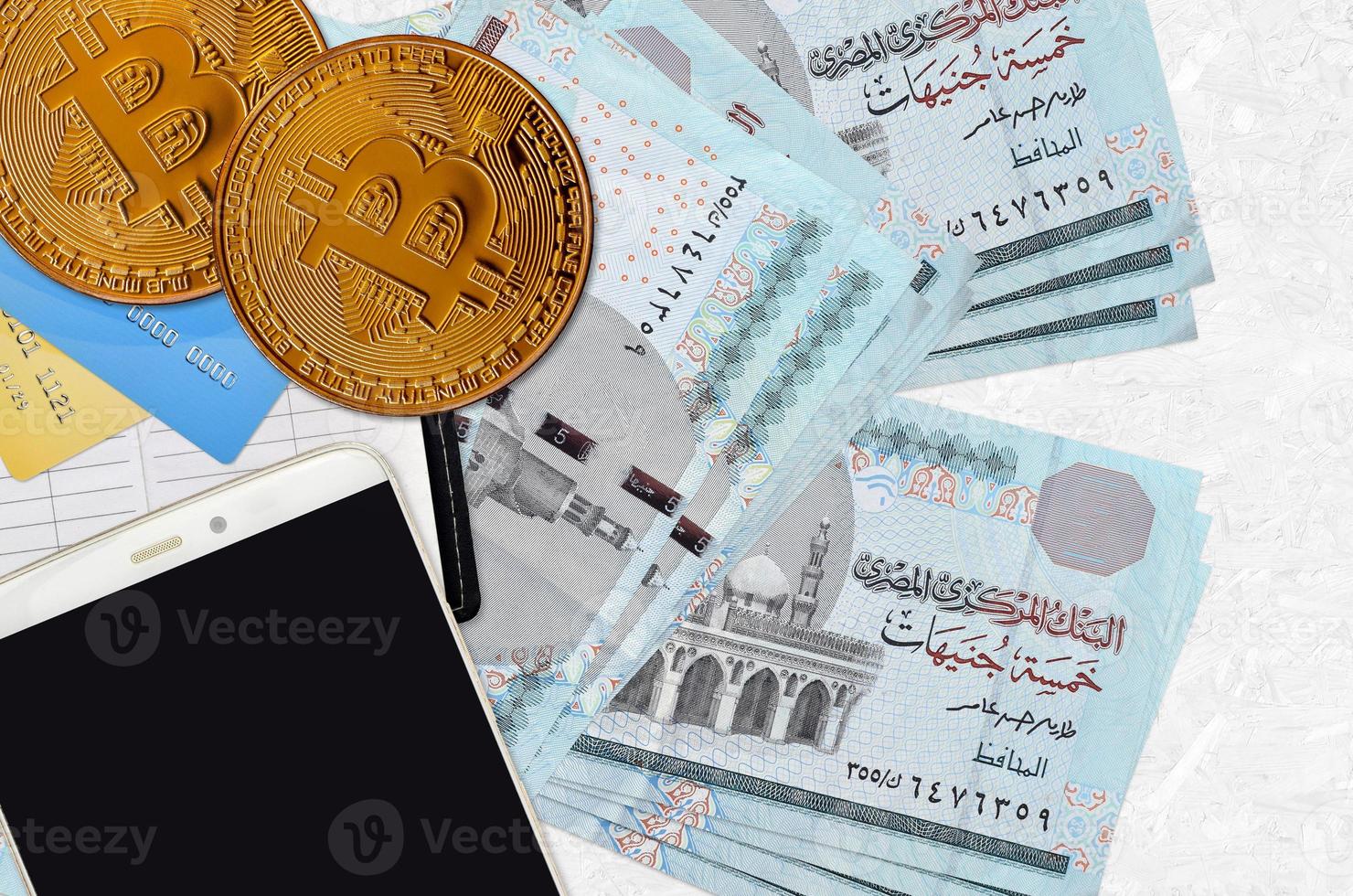 5 Egyptian pounds bills and golden bitcoins with smartphone and credit cards. Cryptocurrency investment concept. Crypto mining or trading photo