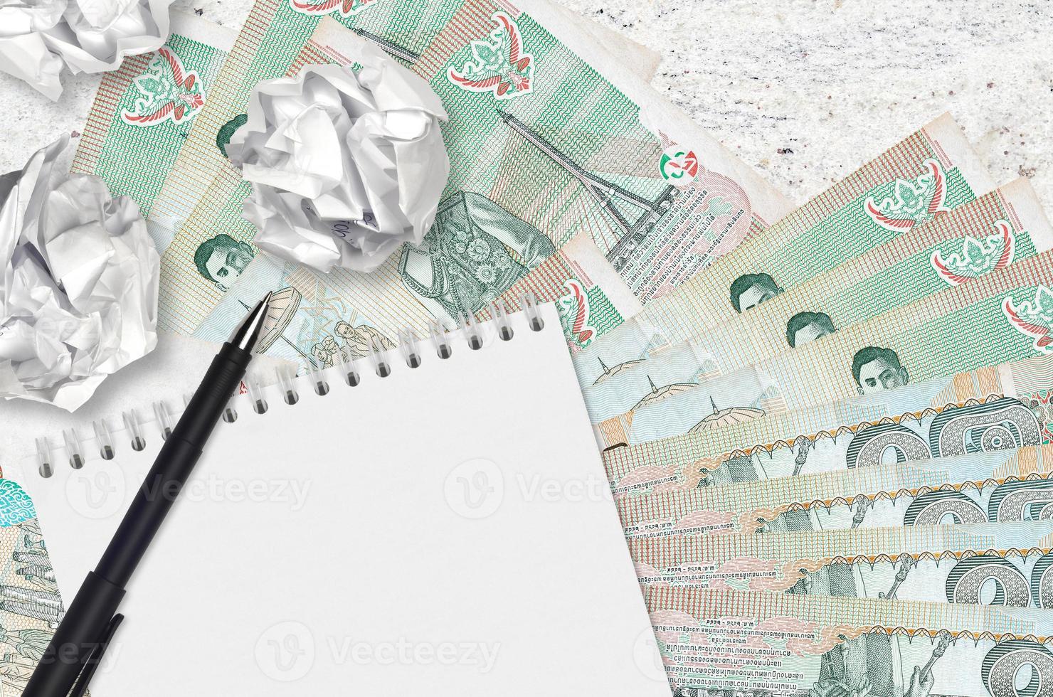 20 Thai Baht bills and balls of crumpled paper with blank notepad. Bad ideas or less of inspiration concept. Searching ideas for investment photo