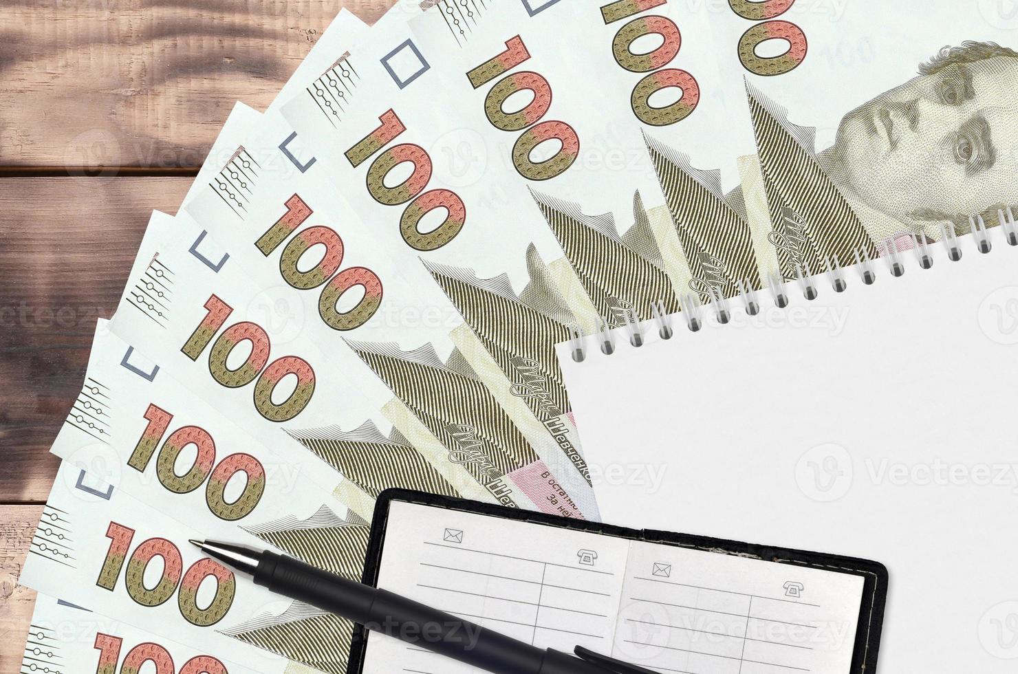 100 Ukrainian hryvnias bills fan and notepad with contact book and black pen. Concept of financial planning and business strategy photo