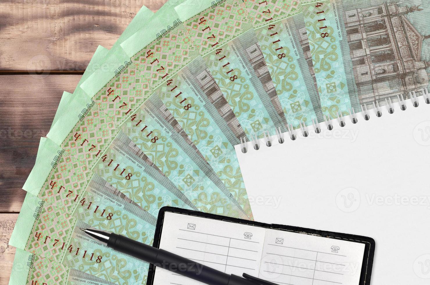 20 Ukrainian hryvnias bills fan and notepad with contact book and black pen. Concept of financial planning and business strategy photo