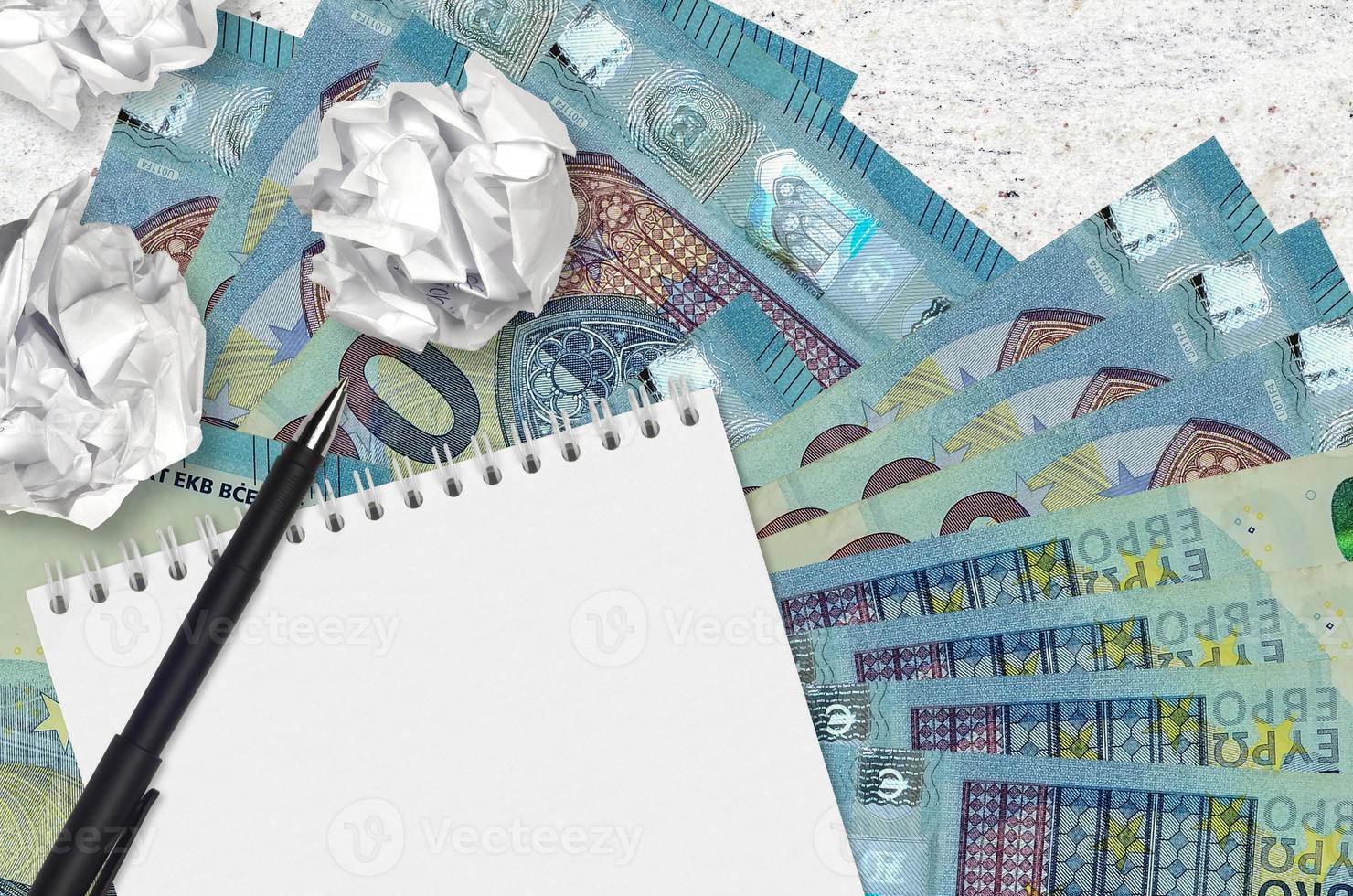 20 euro bills and balls of crumpled paper with blank notepad. Bad ideas or less of inspiration concept. Searching ideas for investment photo