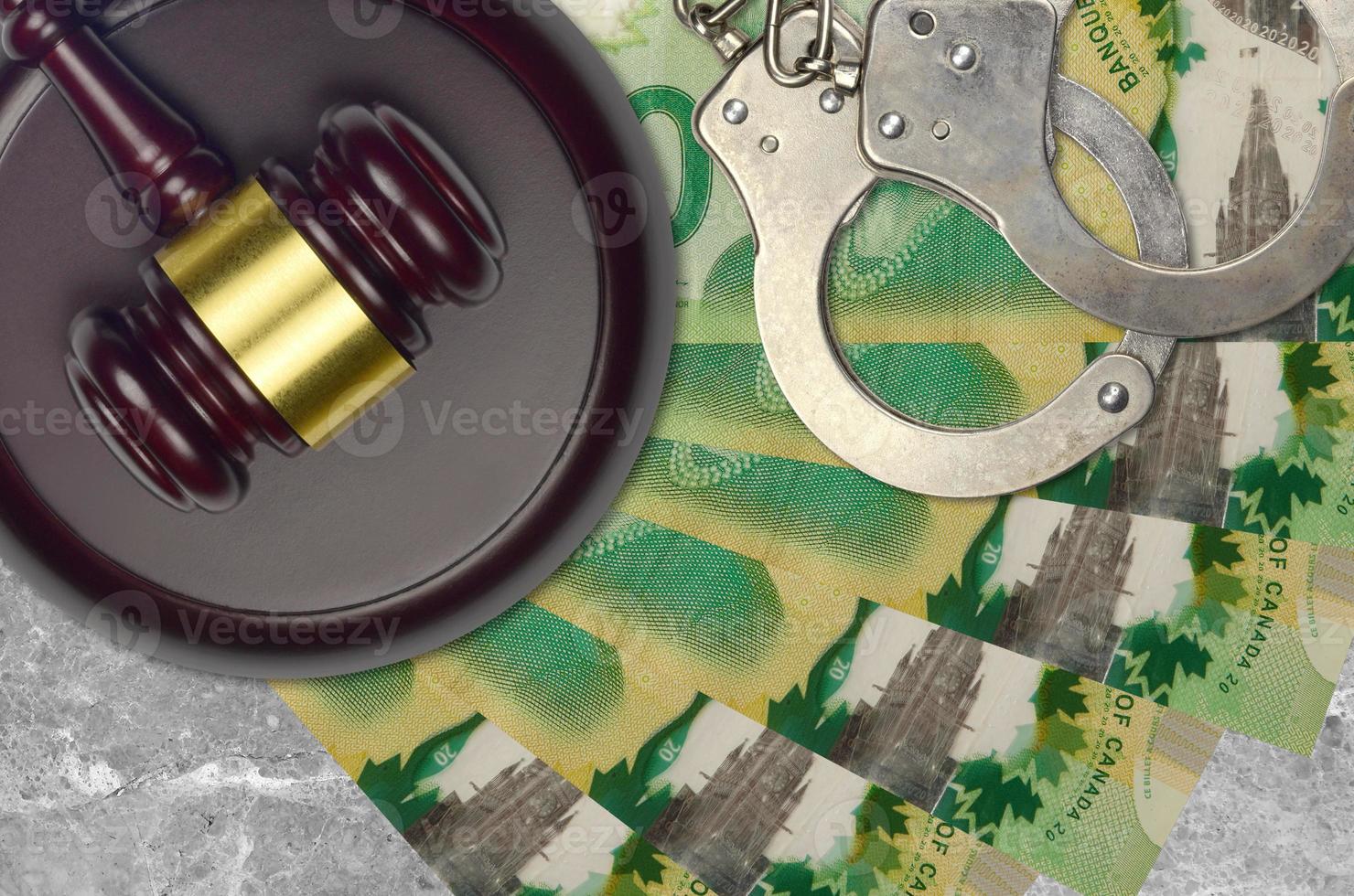 20 Canadian dollars bills and judge hammer with police handcuffs on court desk. Concept of judicial trial or bribery. Tax avoidance photo