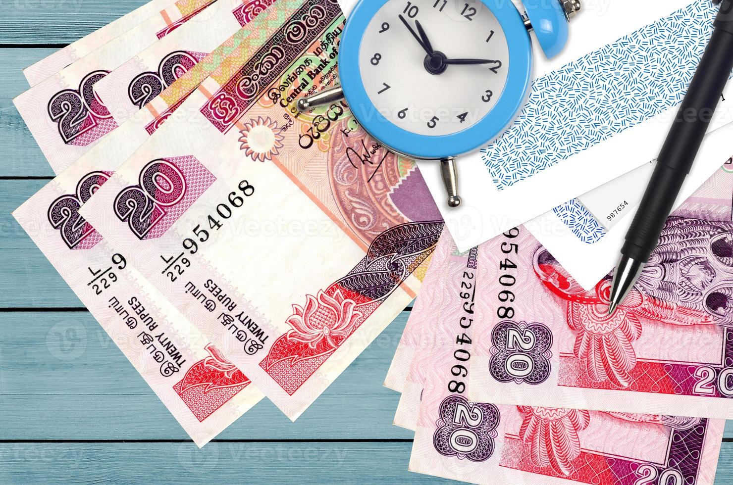 20 Sri Lankan rupees bills and alarm clock with pen and envelopes. Tax