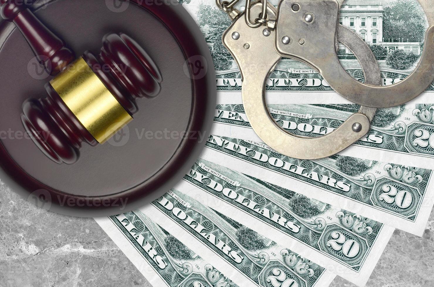 20 US dollars bills and judge hammer with police handcuffs on court desk. Concept of judicial trial or bribery. Tax avoidance photo