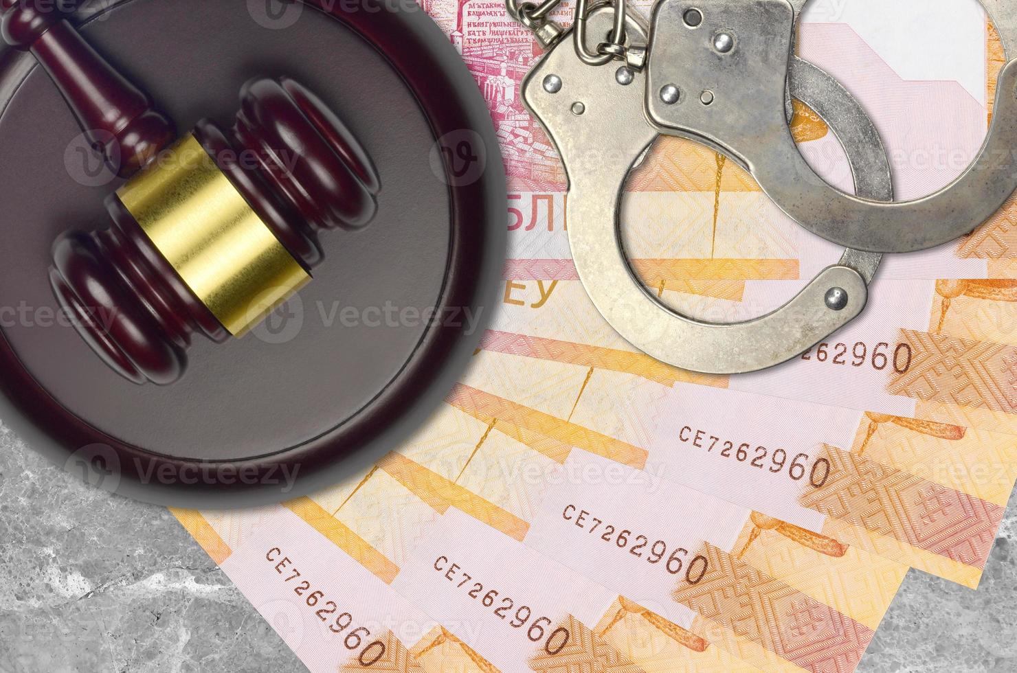 20 Belorussian rubles bills and judge hammer with police handcuffs on court desk. Concept of judicial trial or bribery. Tax avoidance photo