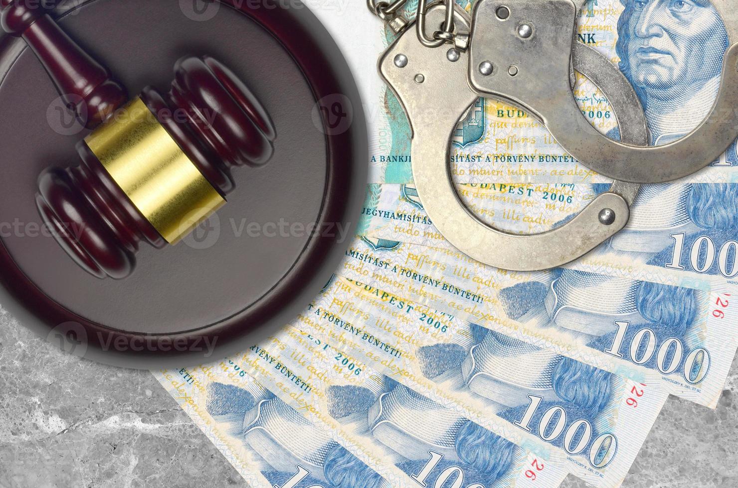 1000 Hungarian forint bills and judge hammer with police handcuffs on court desk. Concept of judicial trial or bribery. Tax avoidance photo