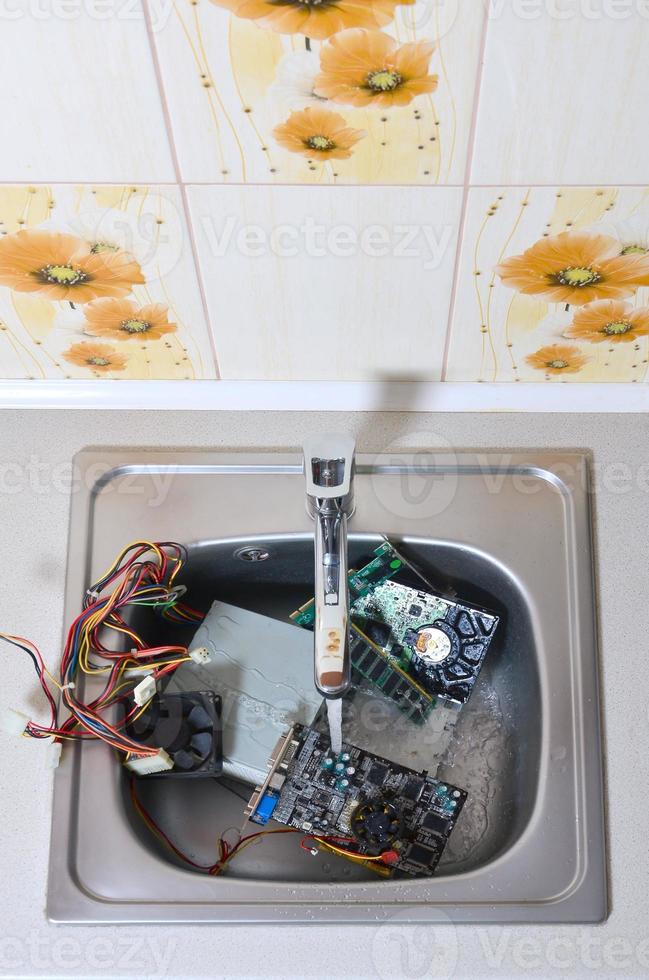 Hardware in kitchen sink under the water flow computer cleaning metaphoric concept photo