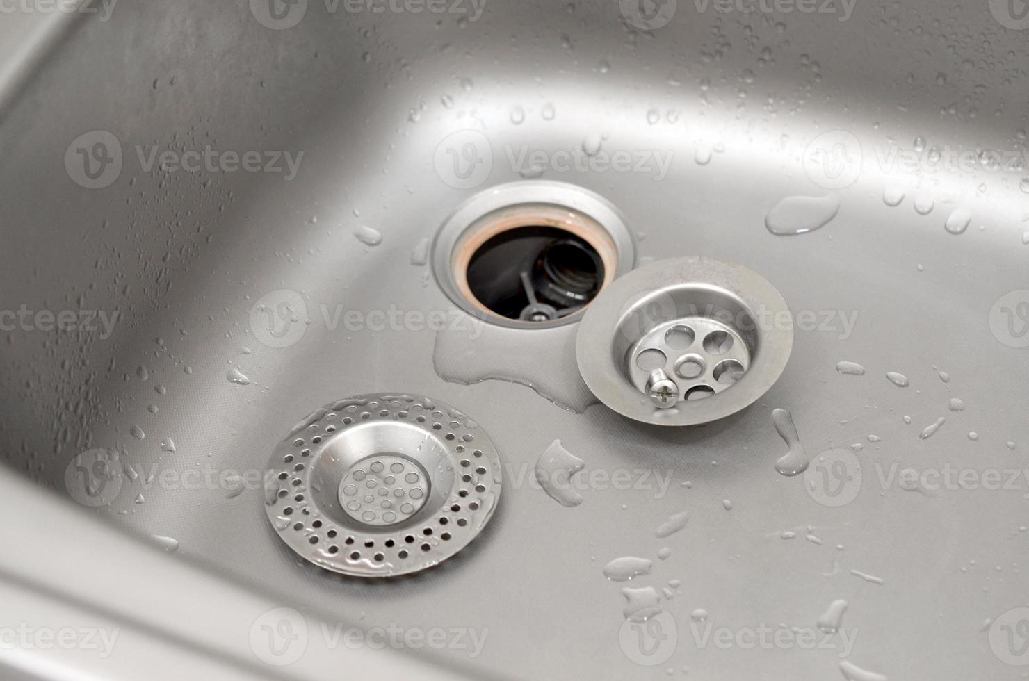 Silvery kitchen sink with a disassembled protective filter during the repair process photo