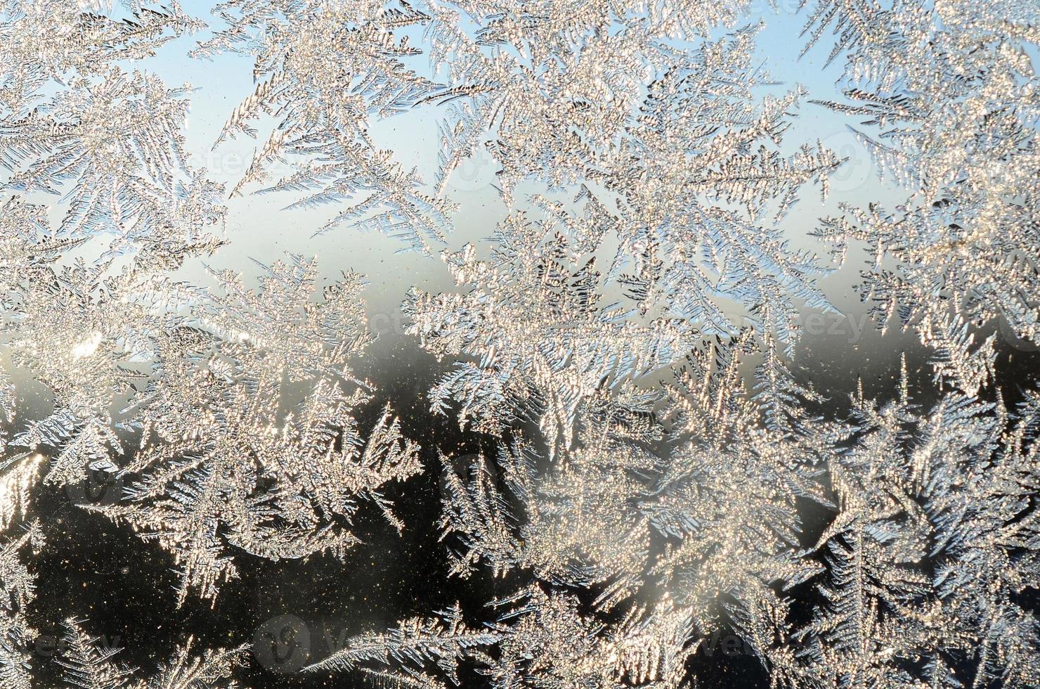 Snowflakes frost rime macro on window glass pane photo