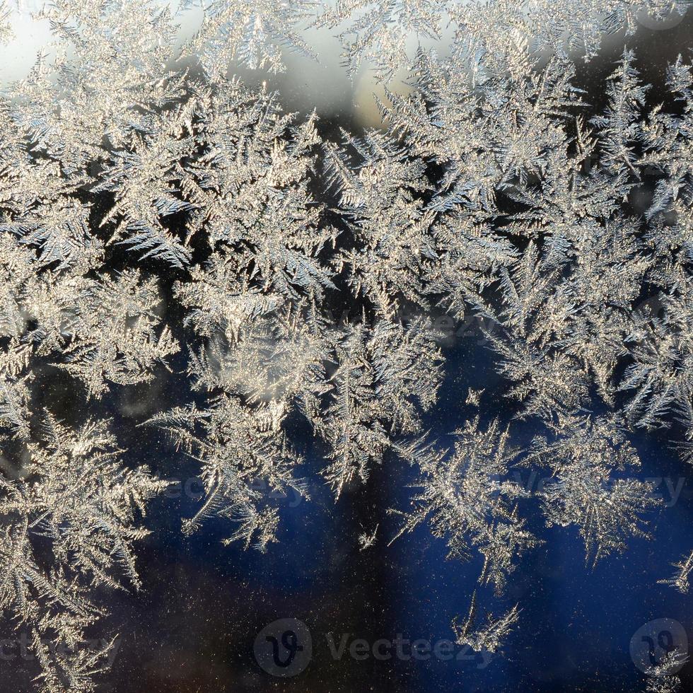 Snowflakes frost rime macro on window glass pane photo