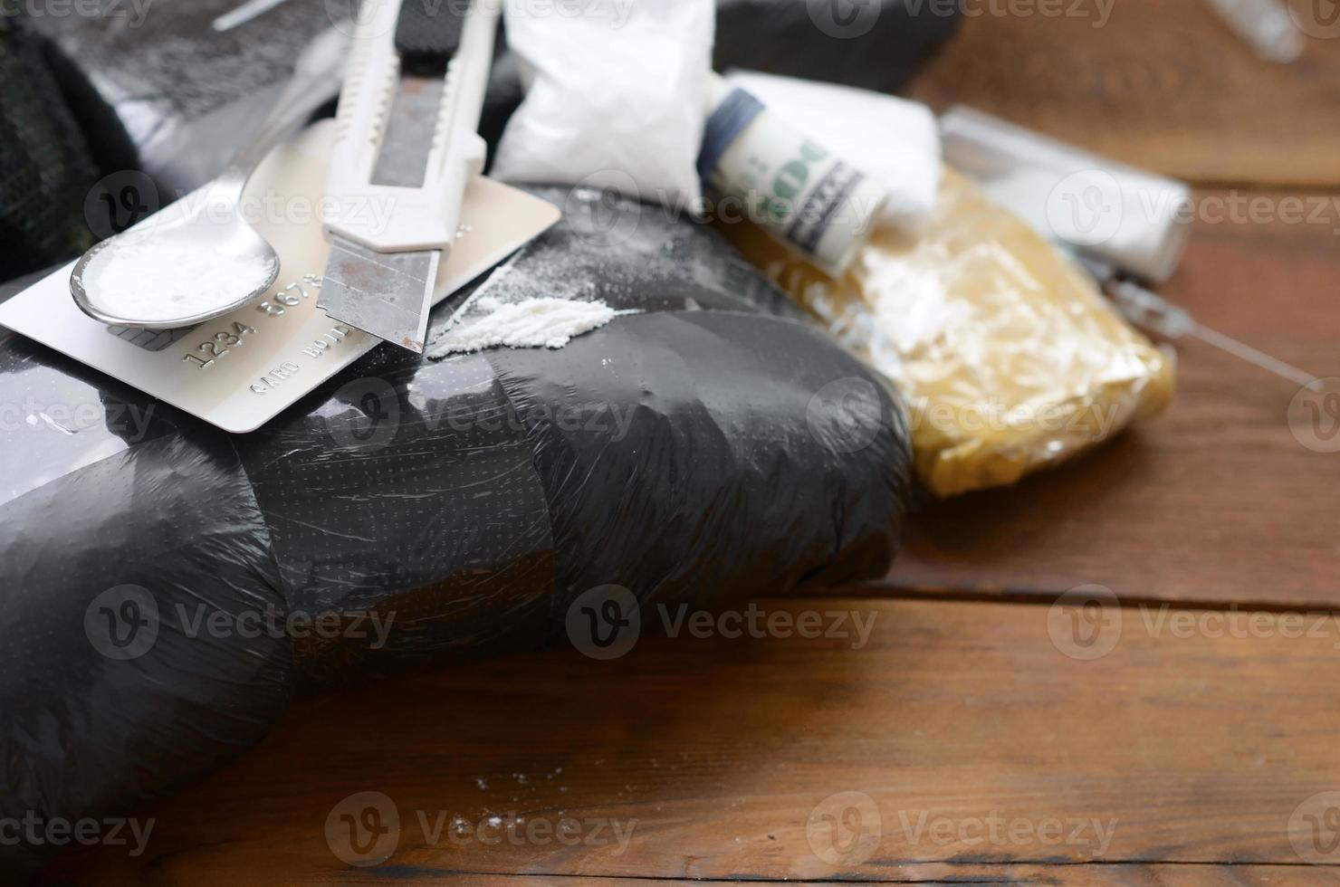 cuchara llena de heroína y cuchillo de papel se encuentra en paquetes de drogas y tarjeta de crédito con rollo de dólares foto