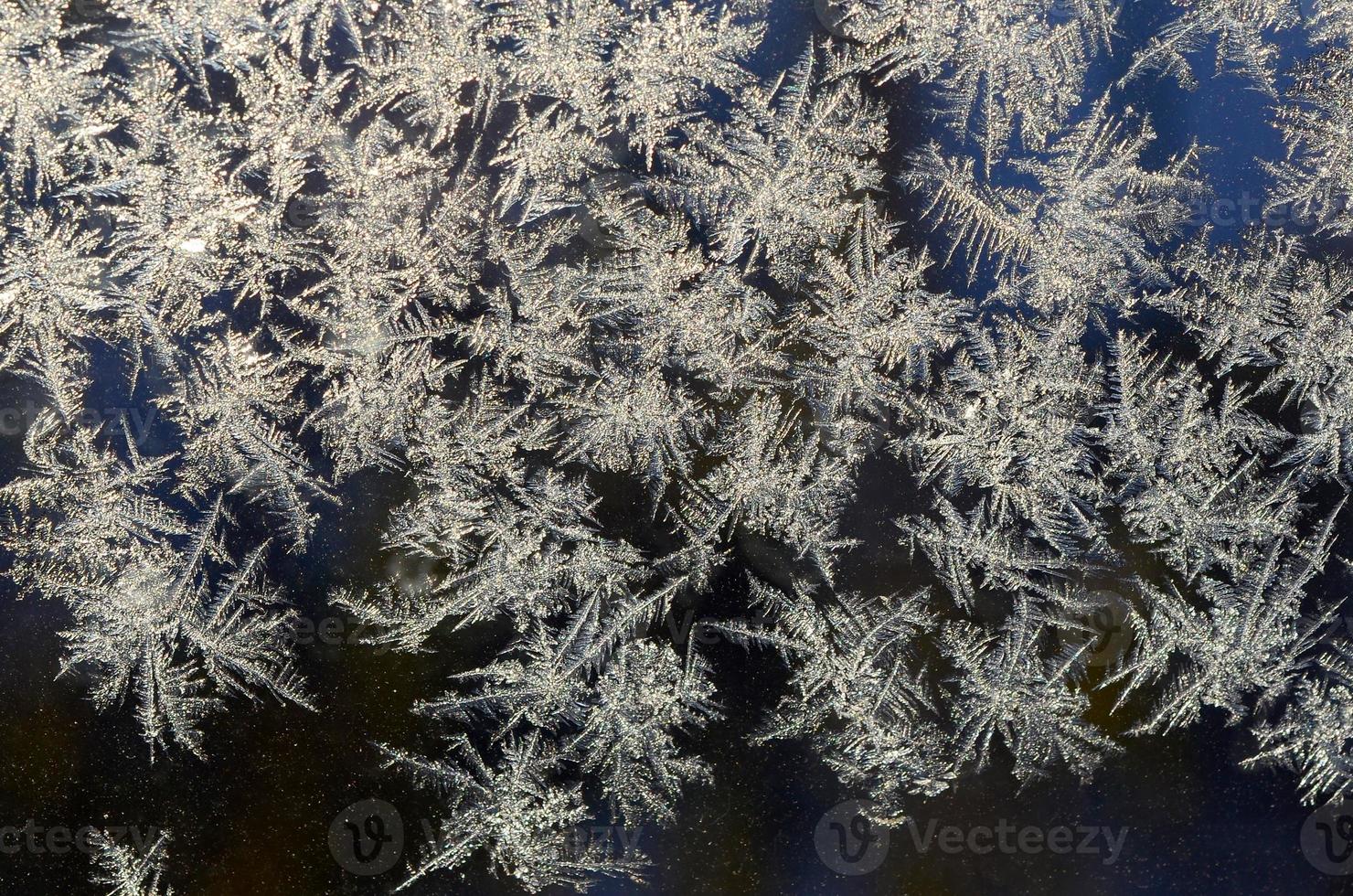 Snowflakes frost rime macro on window glass pane photo