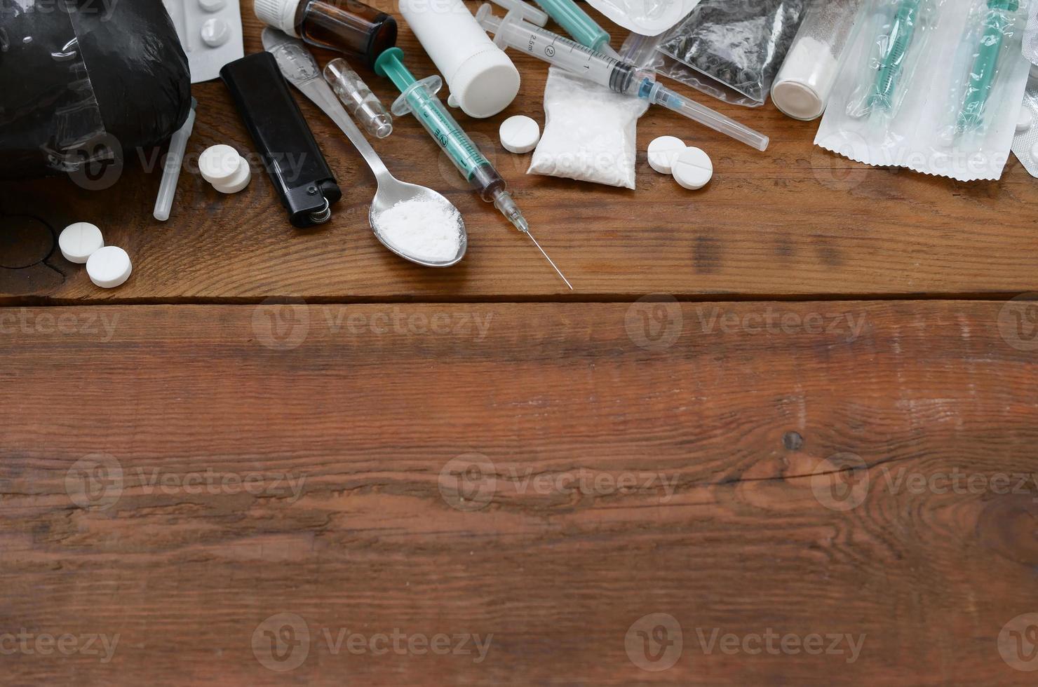 A lot of narcotic substances and devices for the preparation of drugs lie on an old wooden table photo