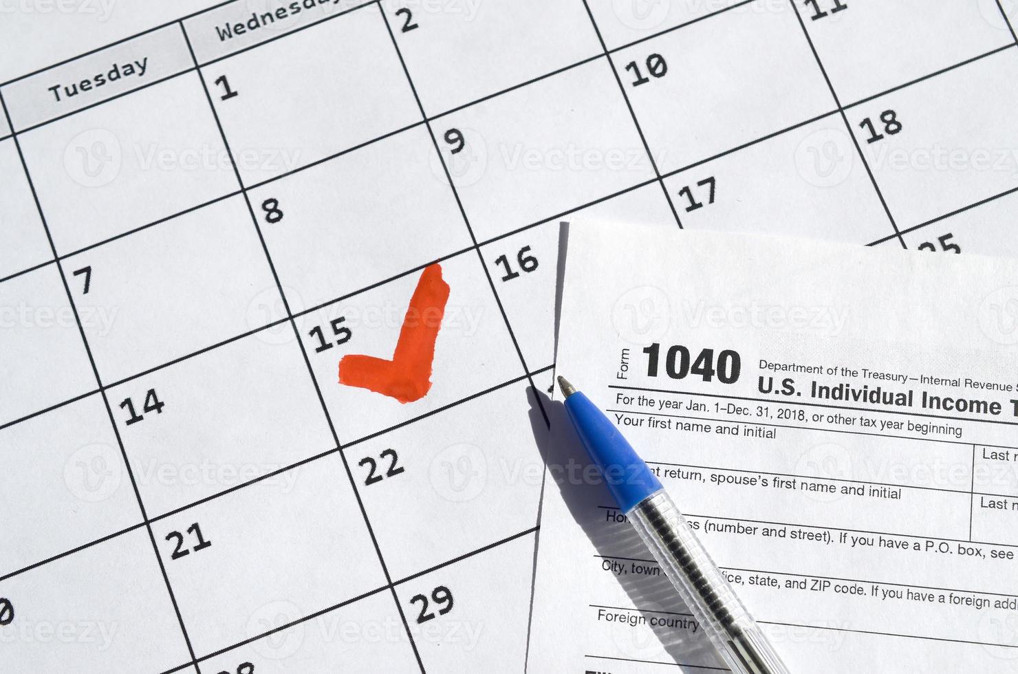1040 declaración de impuestos sobre la renta individual en blanco y bolígrafo en la página del calendario con el 15 de abril marcado foto