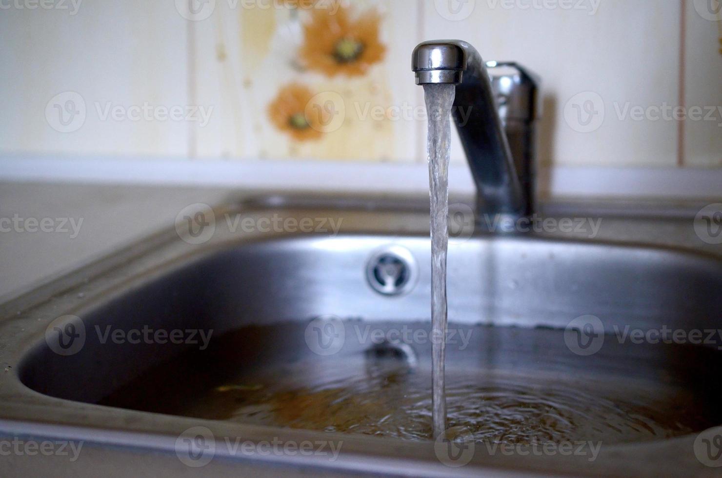 Stainless steel sink plug hole close up full of water and particles of food photo