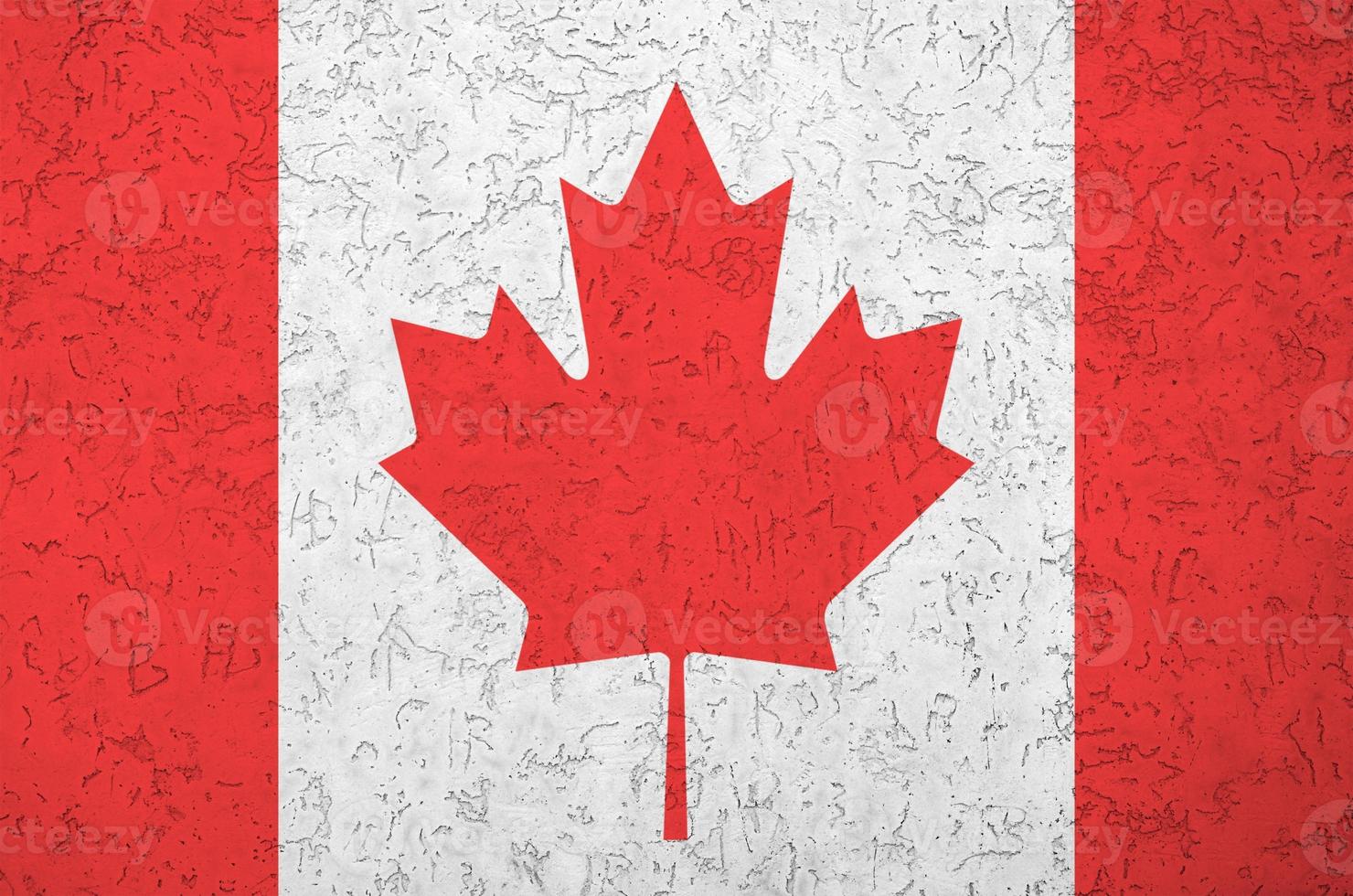 Canada flag depicted in bright paint colors on old relief plastering wall. Textured banner on rough background photo