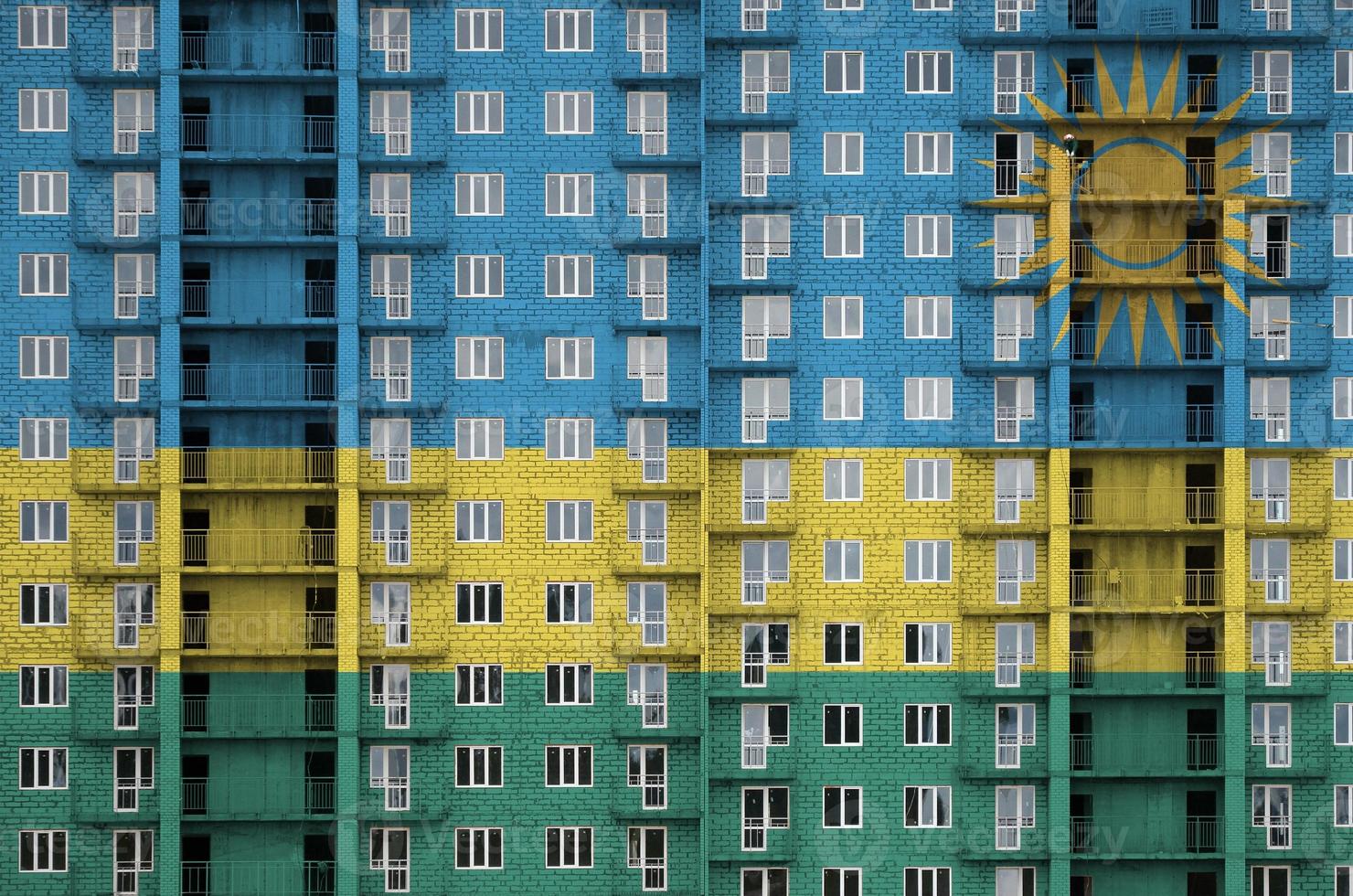 bandera de ruanda representada en colores de pintura en un edificio residencial de varios pisos en construcción. banner texturizado sobre fondo de pared de ladrillo foto