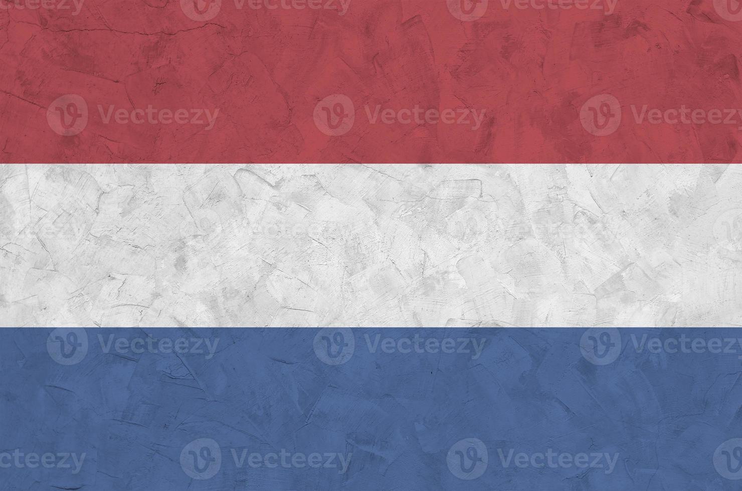 Netherlands flag depicted in bright paint colors on old relief plastering wall. Textured banner on rough background photo