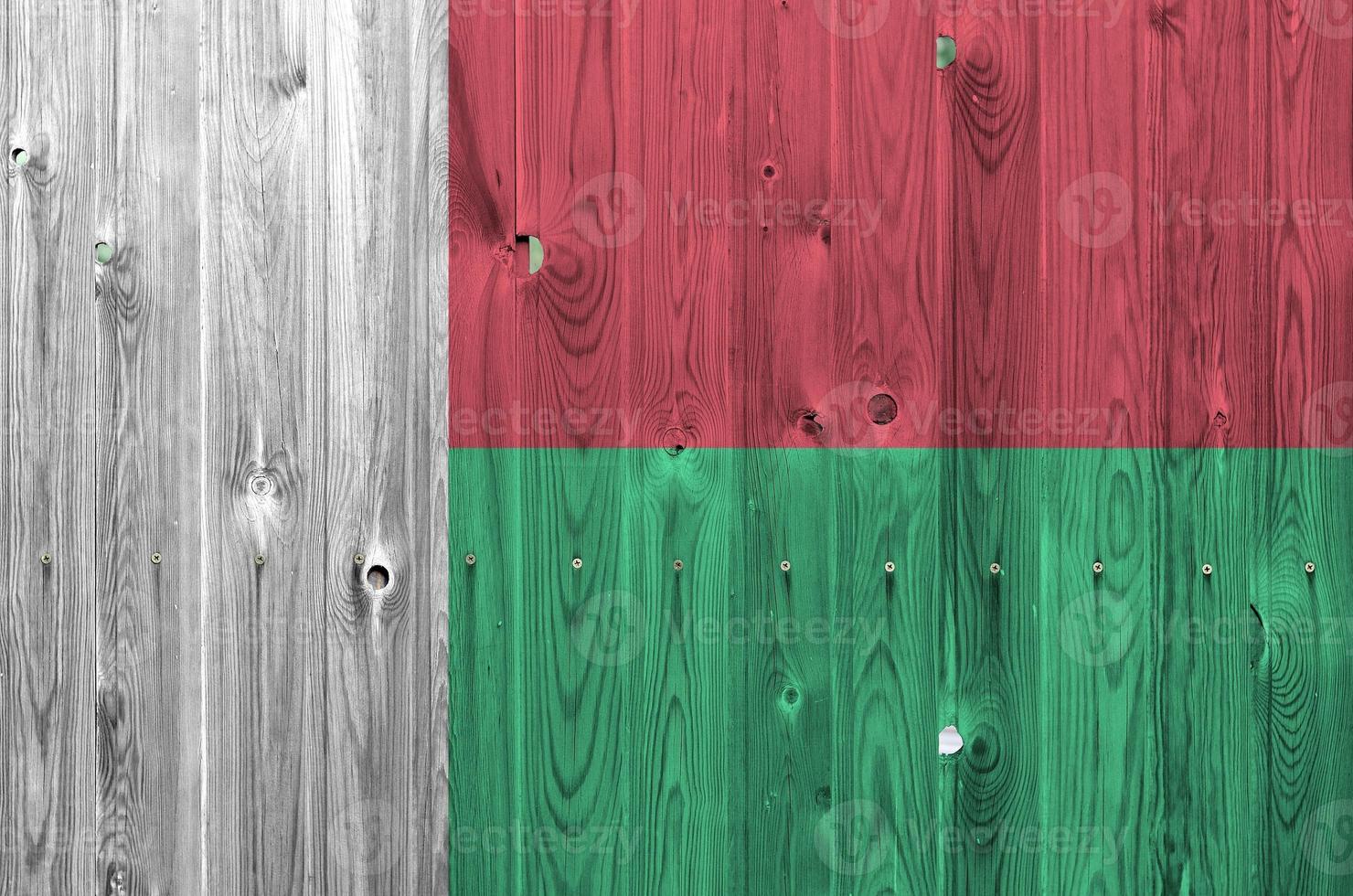 Madagascar flag depicted in bright paint colors on old wooden wall. Textured banner on rough background photo