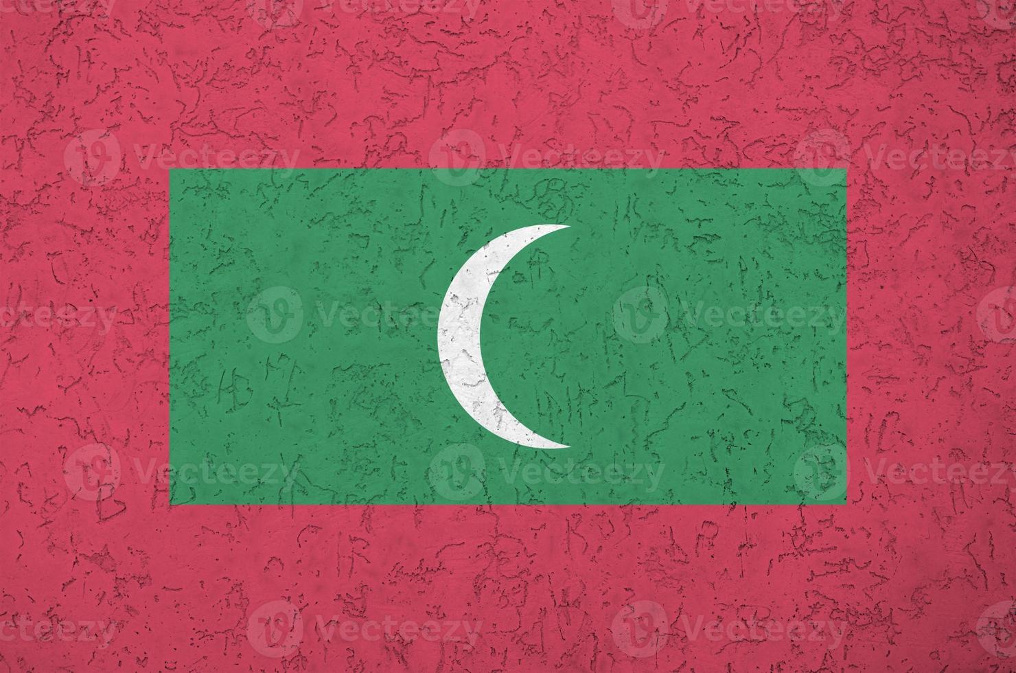 Maldives flag depicted in bright paint colors on old relief plastering wall. Textured banner on rough background photo