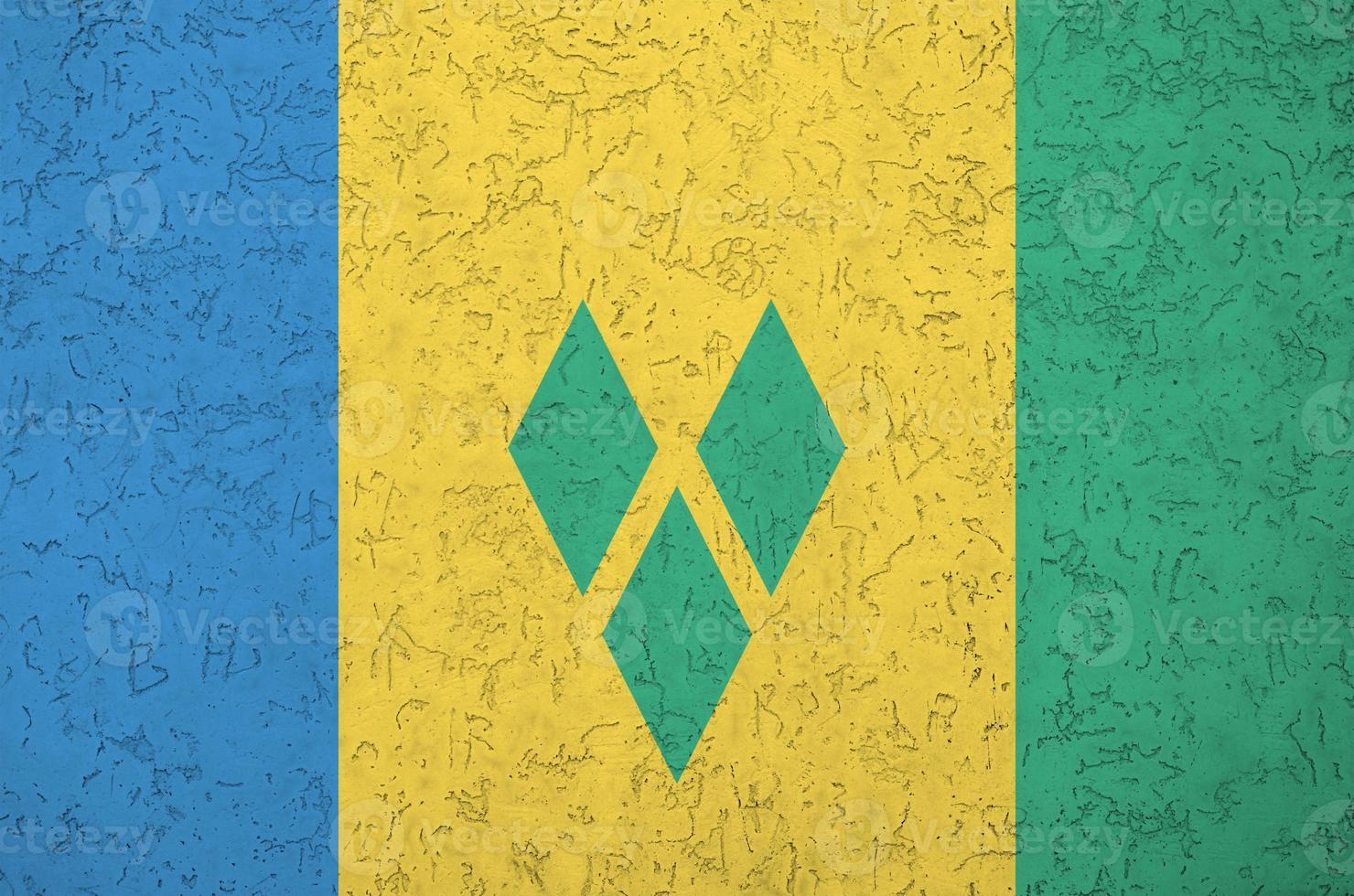 Saint Vincent and the Grenadines flag depicted in bright paint colors on old relief plastering wall. Textured banner on rough background photo